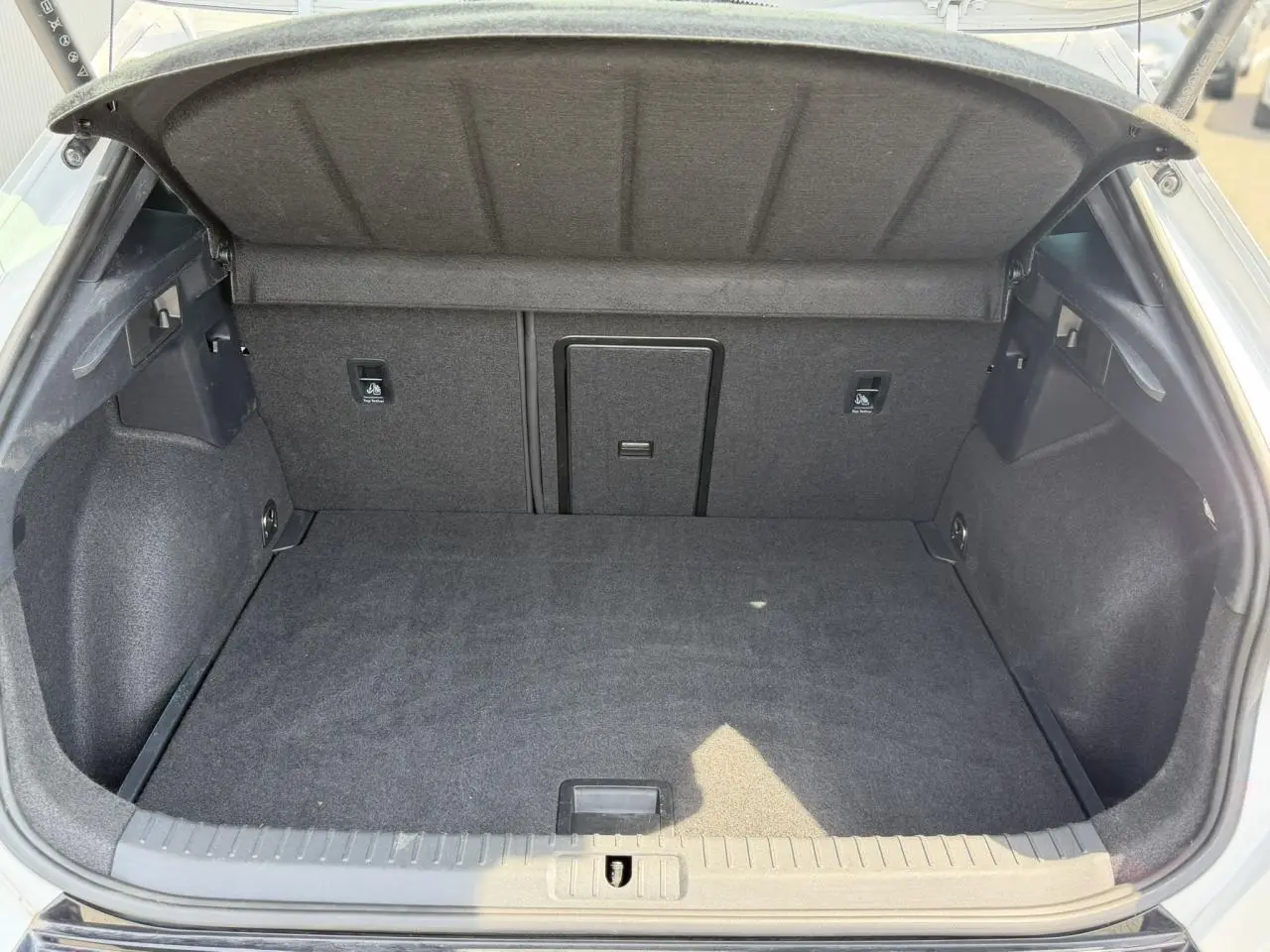 Coffre ouvert vu de l'arrière d'un CUPRA Formentor blanc neige, intérieur de coffre spacieux et tapissé noir.