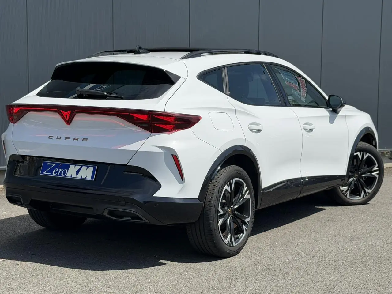 Vue 3/4 arrière droite d'une CUPRA Formentor blanc Neige avec signature lumineuse Tri-LED et jantes alliage noires.