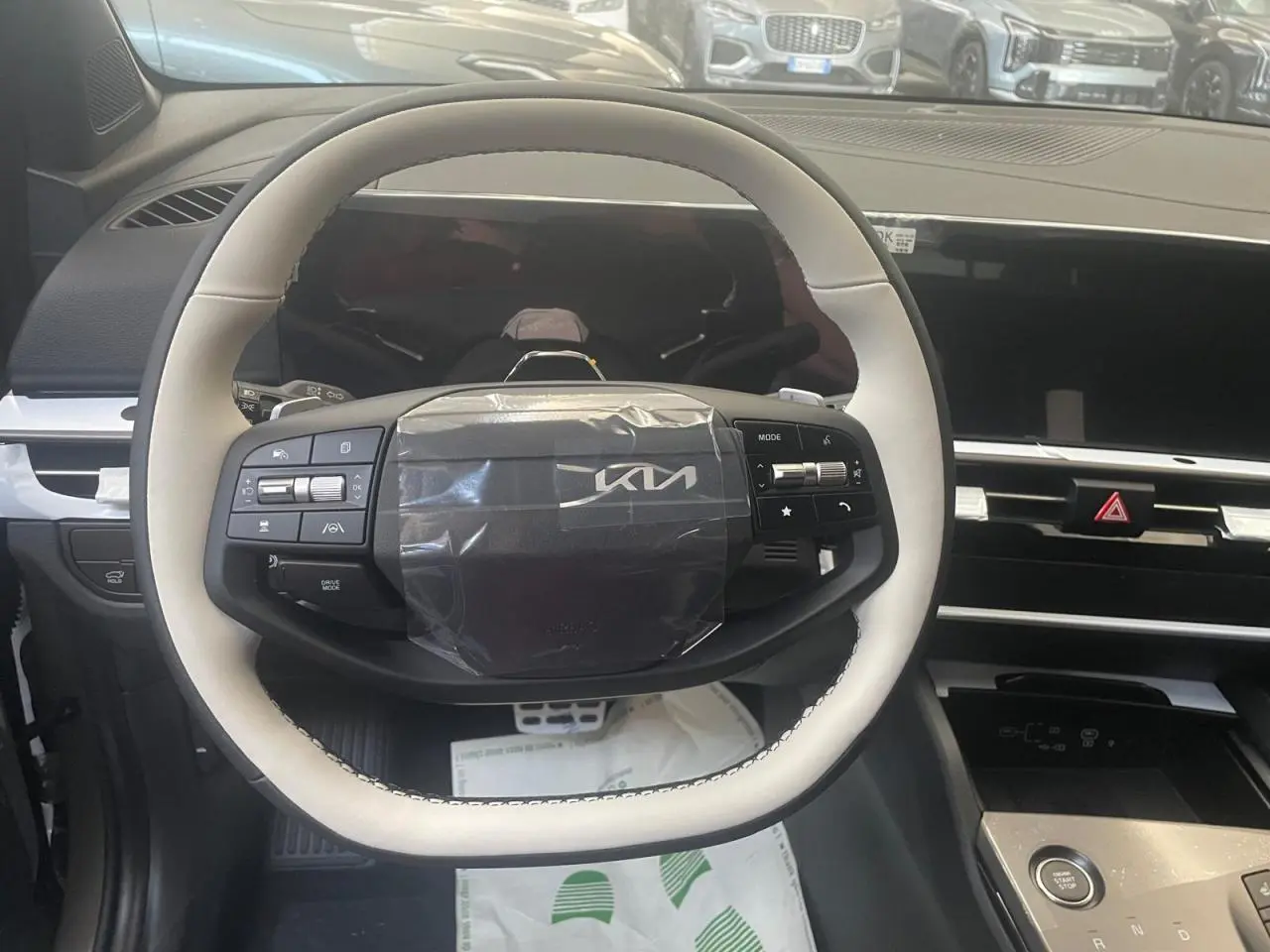 Vue intérieure centrée sur le volant blanc et noir du KIA SPORTAGE Hybride 2026 avec tableau de bord moderne.
