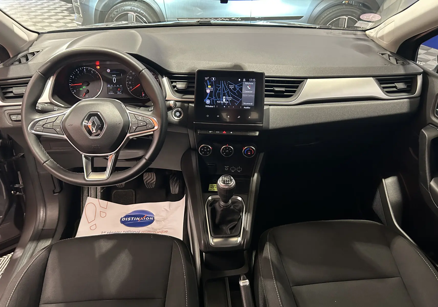 Vue intérieure frontale du tableau de bord du Renault Captur gris 2022, avec volant multifonction et écran tactile GPS.