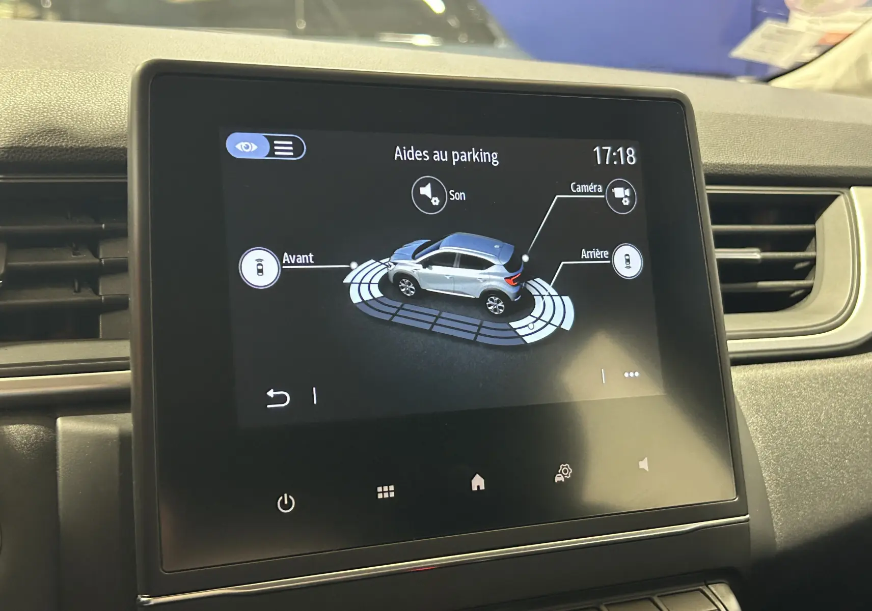 Écran tactile intérieur montrant l'aide au parking avec une illustration 3D d'un Renault Captur gris vue de côté.