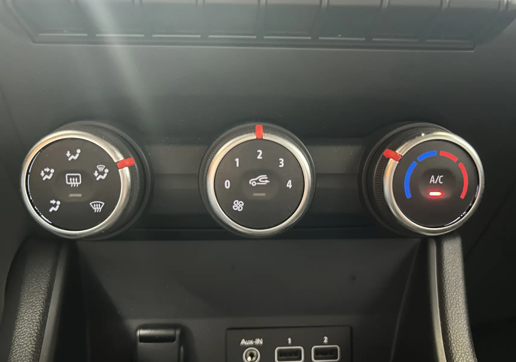Gros plan sur les commandes de climatisation manuelle du Renault Captur gris, avec réglages de température, ventilation et air conditionné.