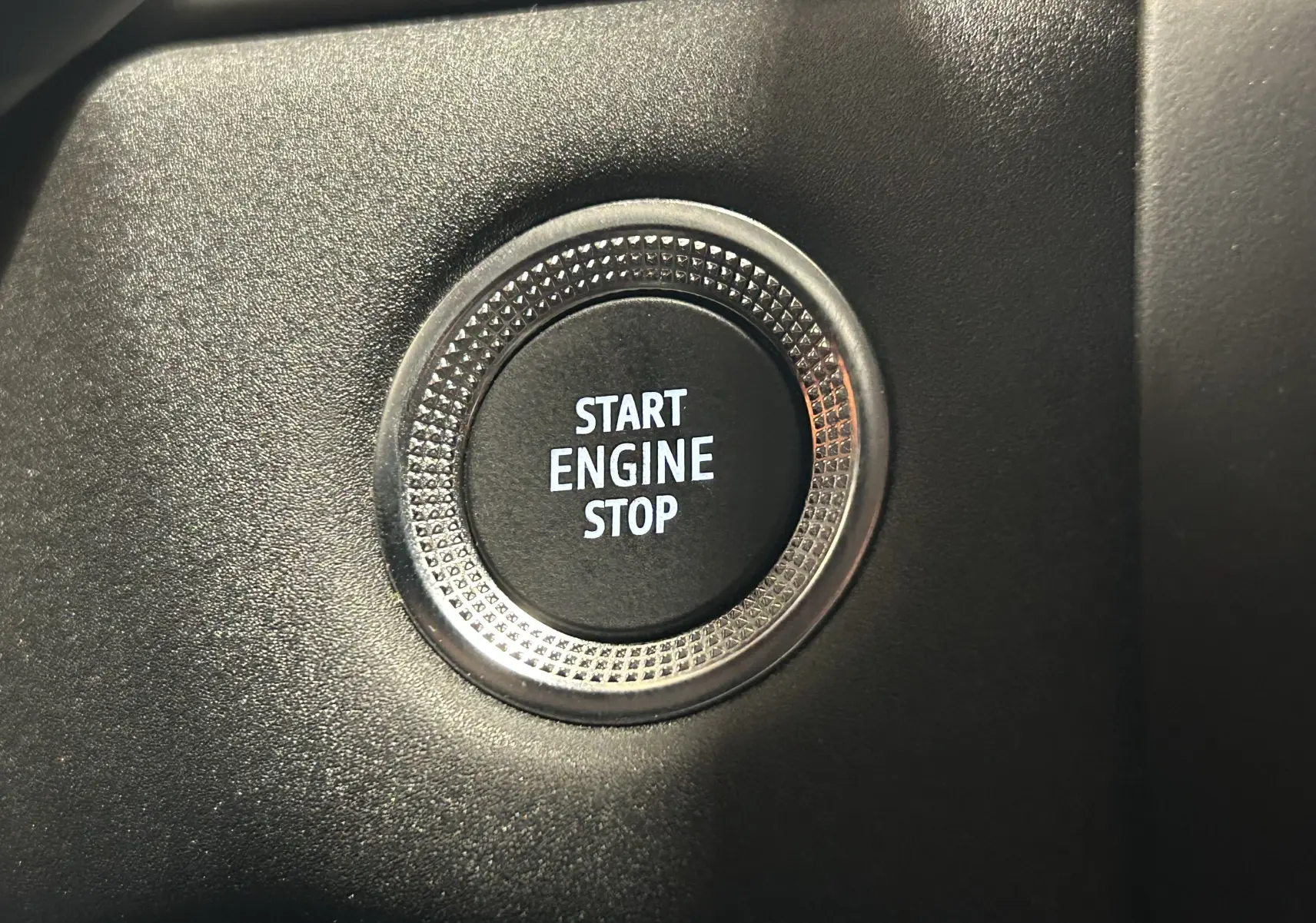 Gros plan sur le bouton Start Engine Stop entouré d’un cercle texturé dans l’habitacle noir du Renault Captur gris.