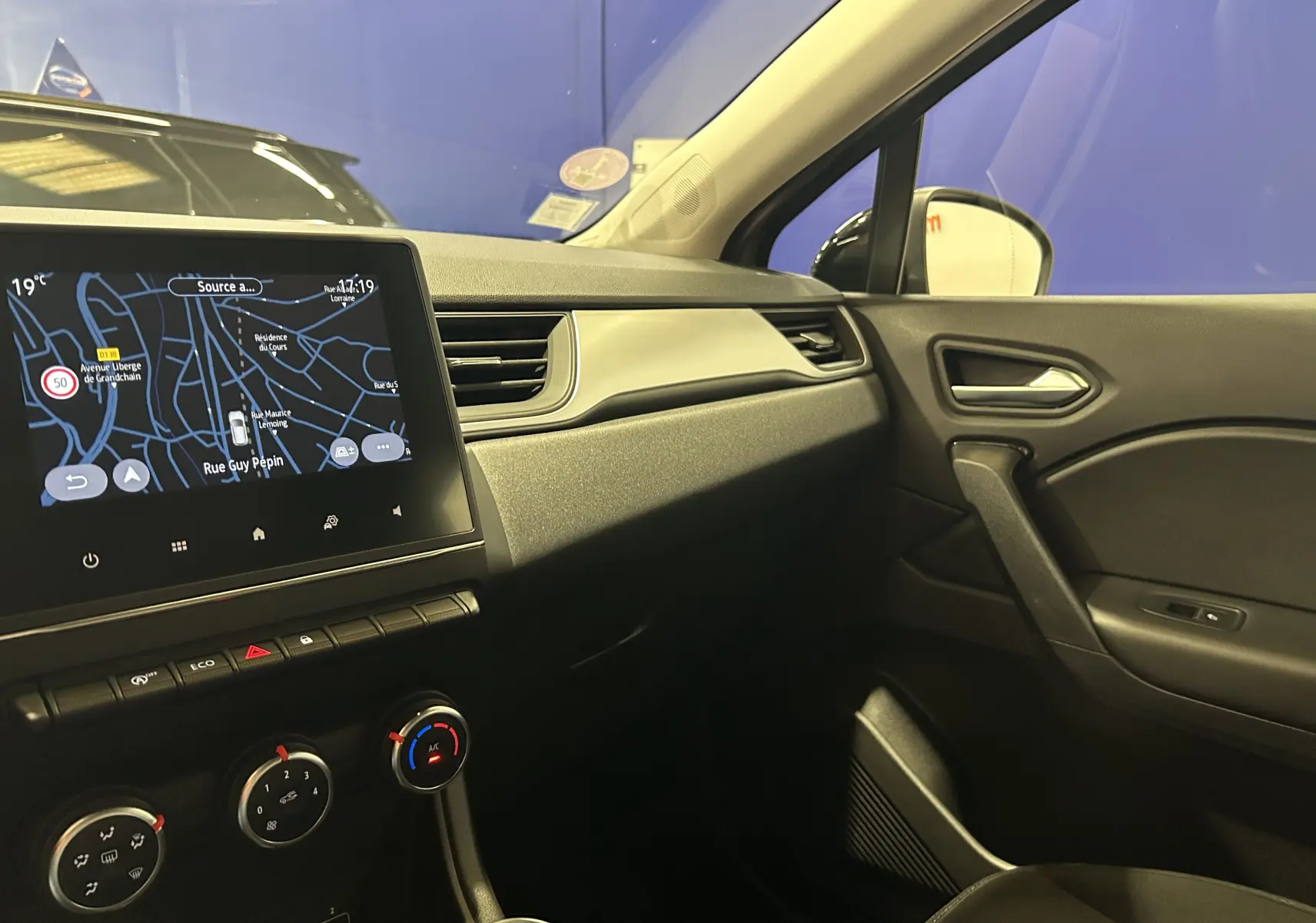 Vue intérieure côté passager du Renault Captur gris 2022, avec écran GPS tactile et commandes de climatisation visibles.