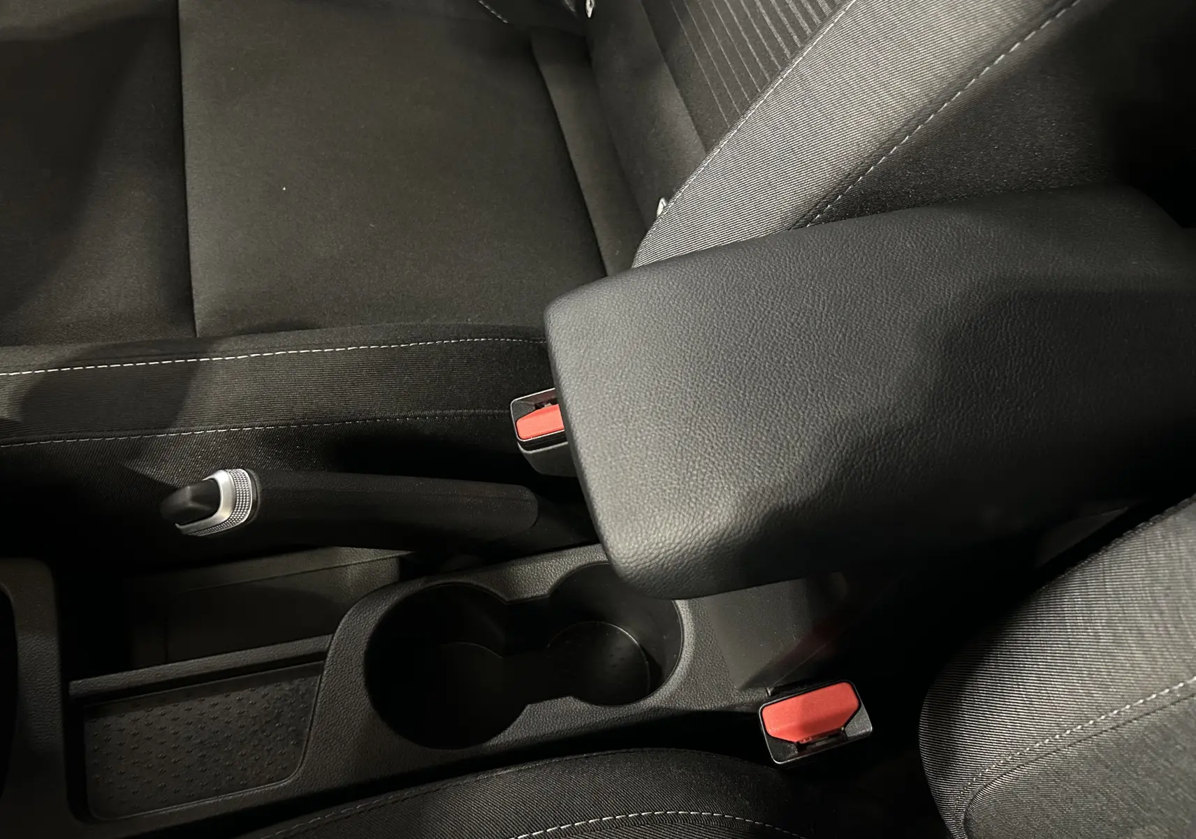 Détail de l'accoudoir central noir et frein à main manuel sur les sièges tissu gris du Renault Captur 2022.