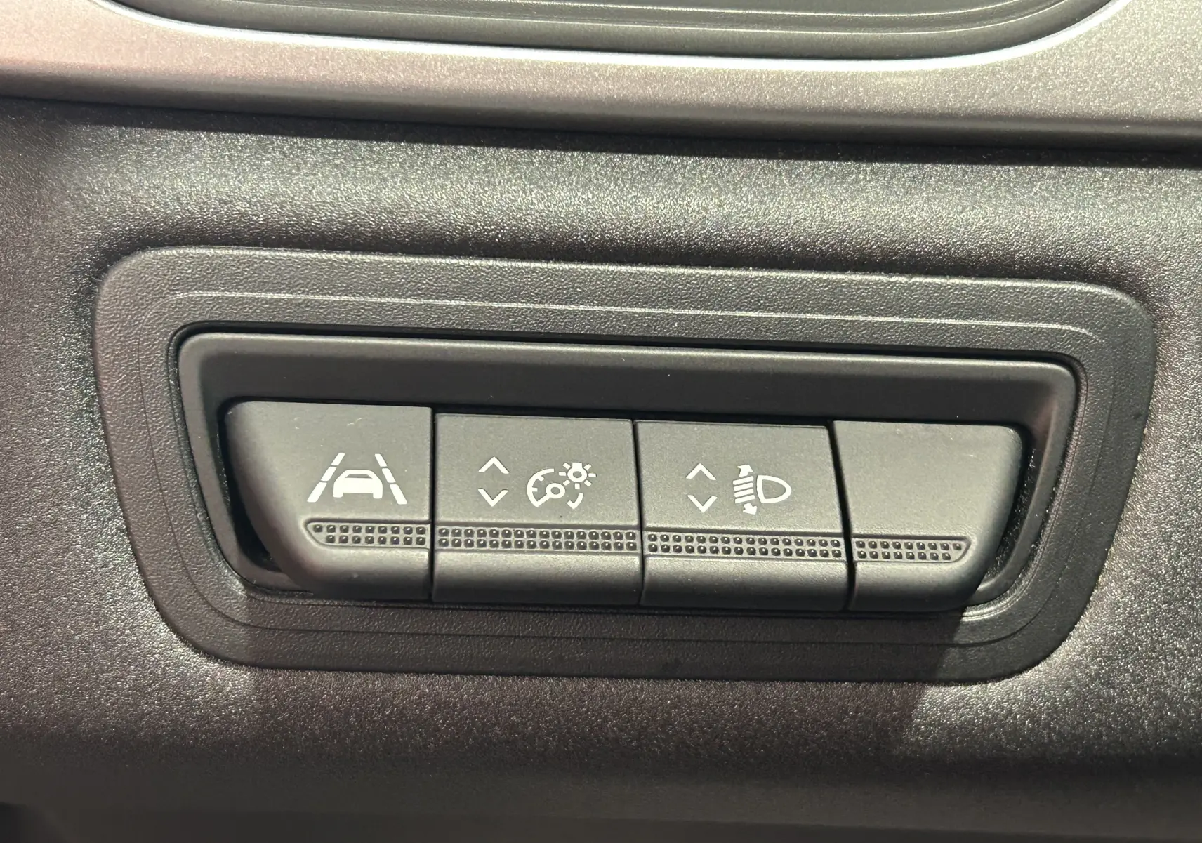 Gros plan sur les boutons de réglage d'assistance à la conduite et d'éclairage du tableau de bord d'un Renault Captur gris.