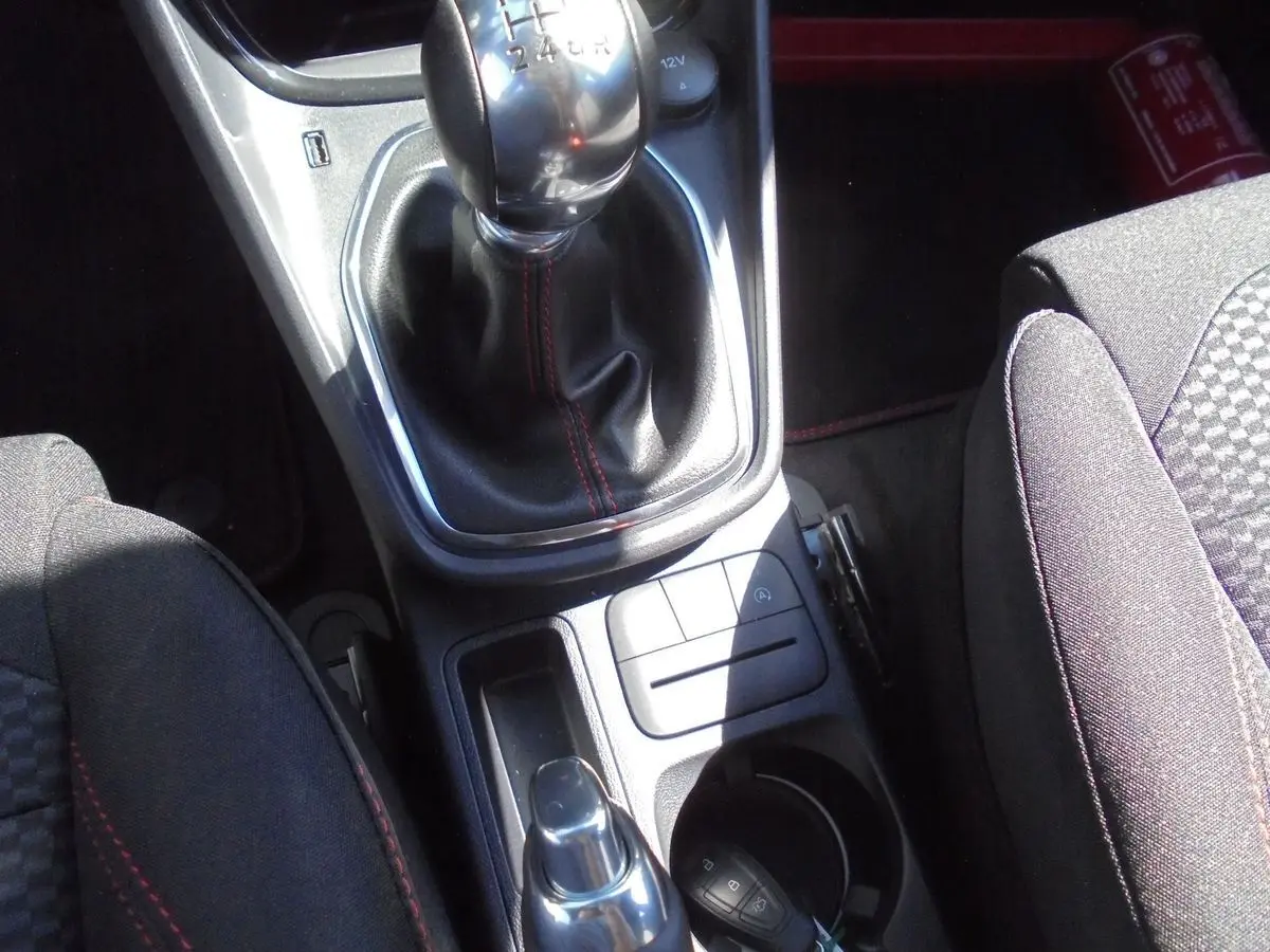 Gros plan sur la console centrale du Ford Puma 2022 avec levier de vitesses manuel et sièges tissu noir à surpiqûres rouges.