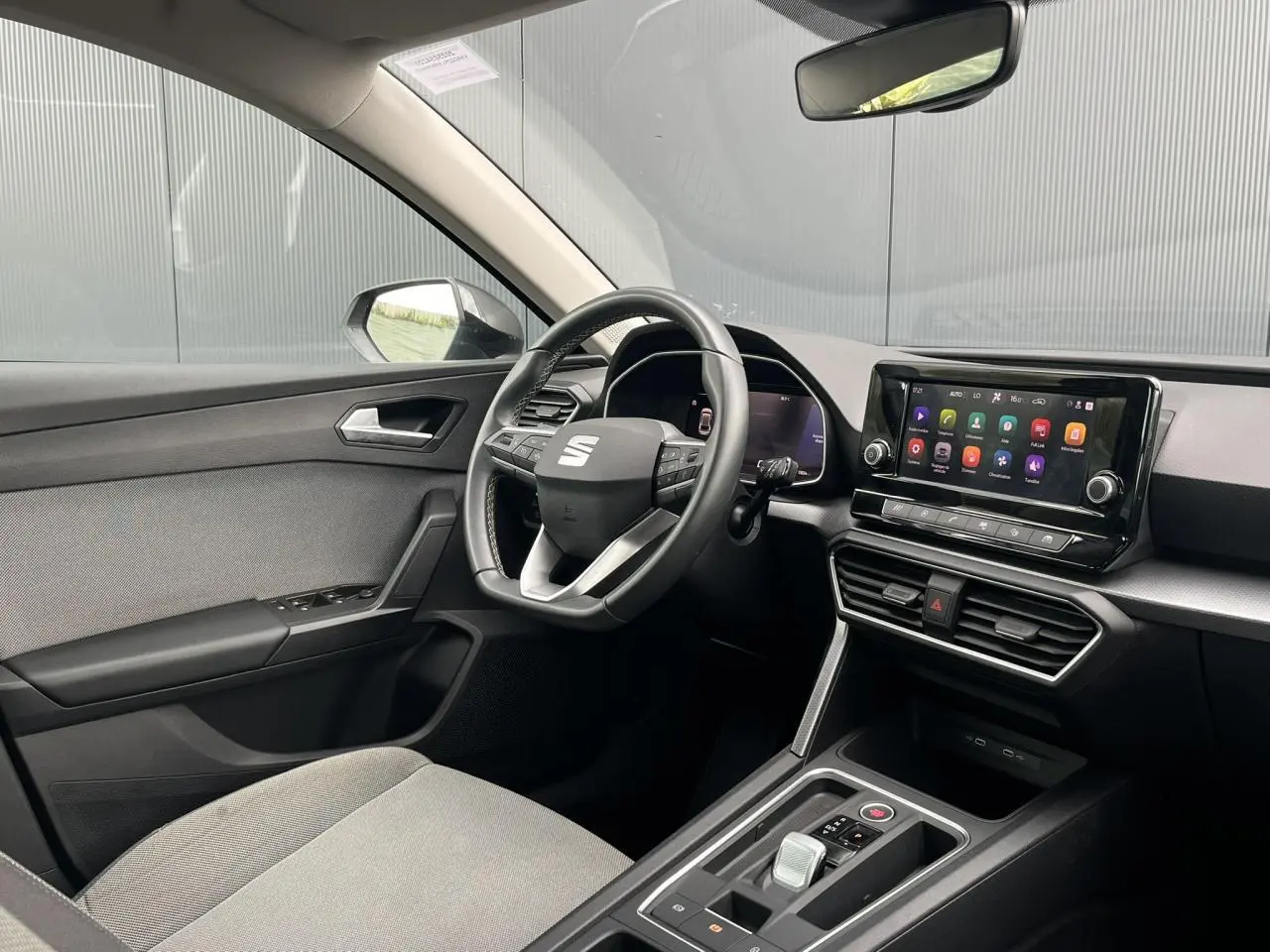 Intérieur avant droit du SEAT Leon 2024 noir Minuit, volant cuir multifonction et écran tactile central visible.