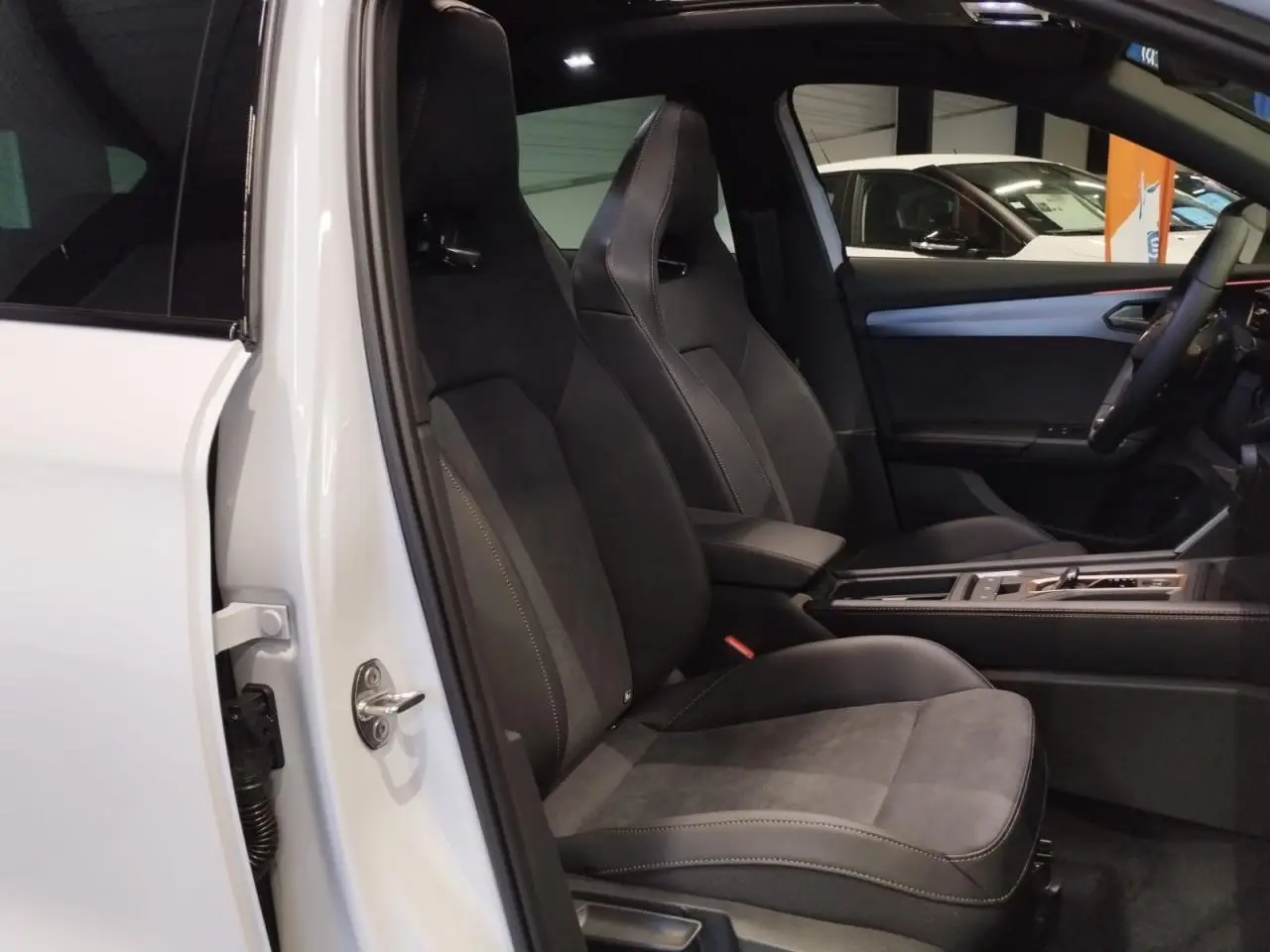 Vue intérieure côté conducteur du CUPRA Formentor blanc Nevada, sièges baquets suédine noire avec surpiqûres cuivrées.