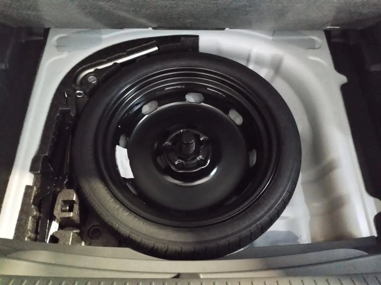 Vue rapprochée de la roue de secours compacte noire dans le coffre du CUPRA Formentor Nevada White 2026.