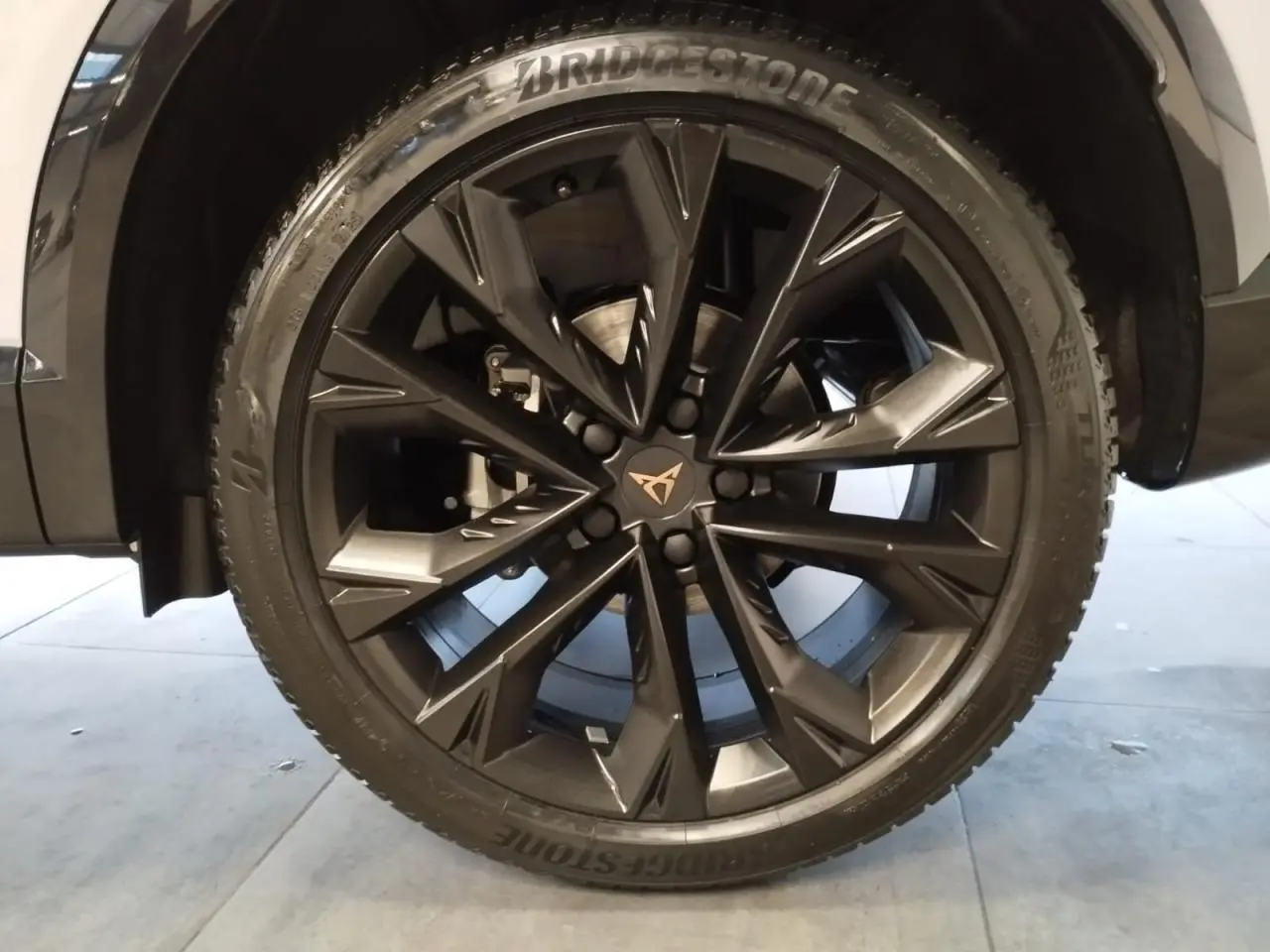 Gros plan sur la jante alliage 19'' Sandstorm noire du CUPRA Formentor Nevada White, avec logo Cupra central.