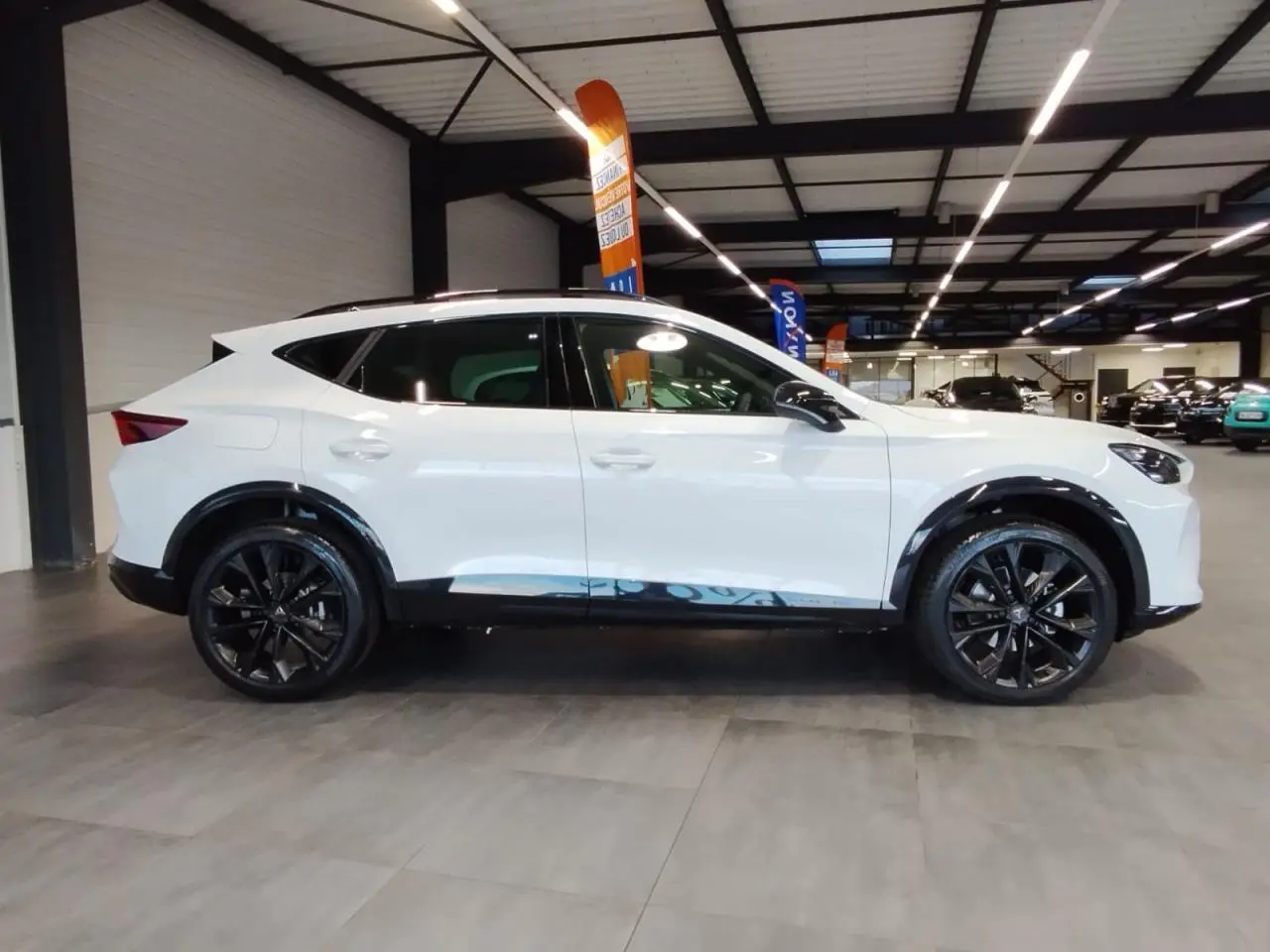 Vue de profil côté gauche du CUPRA Formentor blanc Nevada avec jantes alliage noires et bas de caisse contrastants noirs.