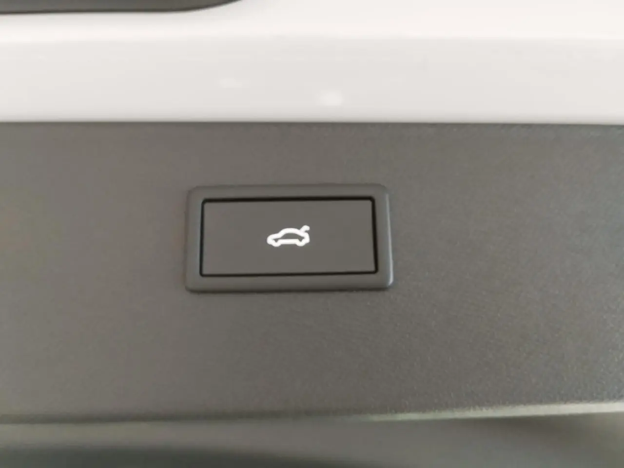 Bouton d'ouverture électrique du hayon sur fond noir, intérieur du coffre du CUPRA Formentor blanc Nevada White.