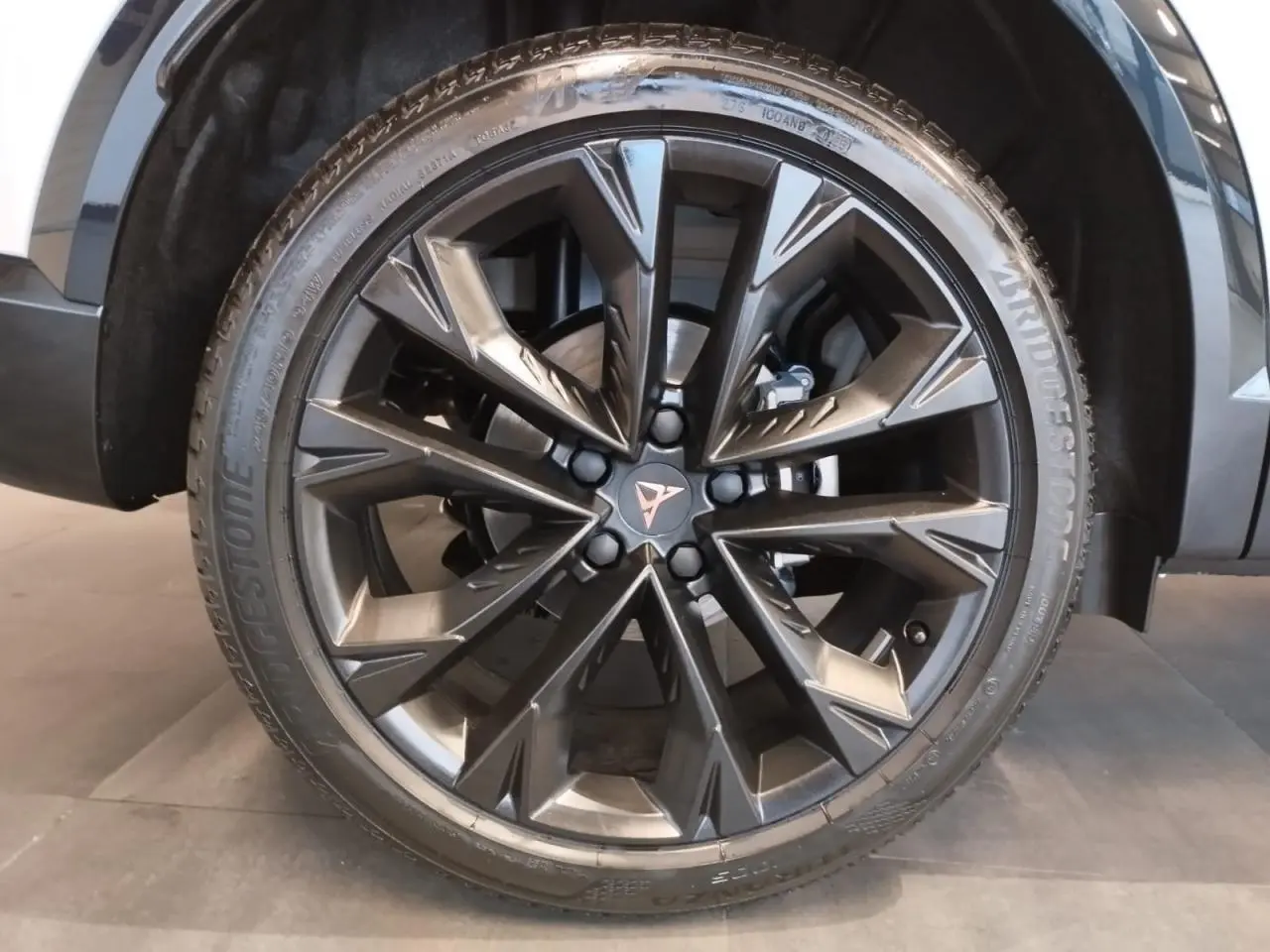 Gros plan sur la jante alliage noire 19'' Sandstorm du CUPRA Formentor Nevada White, avec logo Cupra central cuivré.