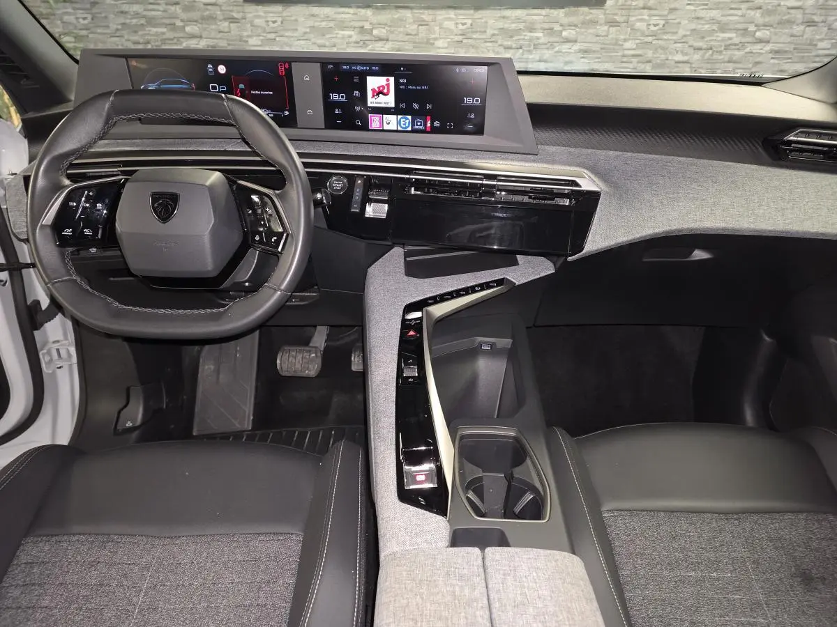Intérieur Peugeot 3008 2025 vue du poste de conduite, volant compact cuir noir et double écran HD panoramique.
