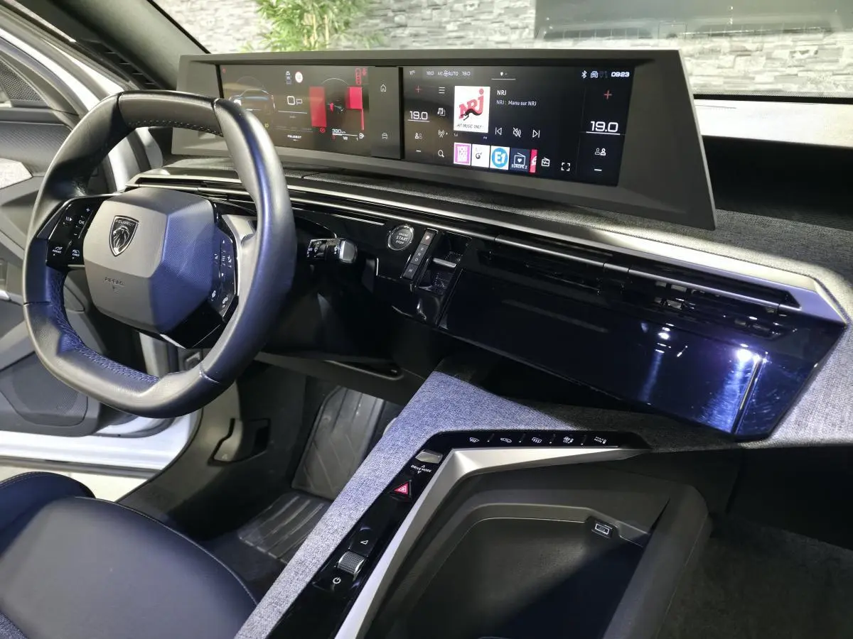 Vue intérieure du tableau de bord du Peugeot 3008 blanc 2025, avec volant compact cuir noir et double écran HD panoramique.