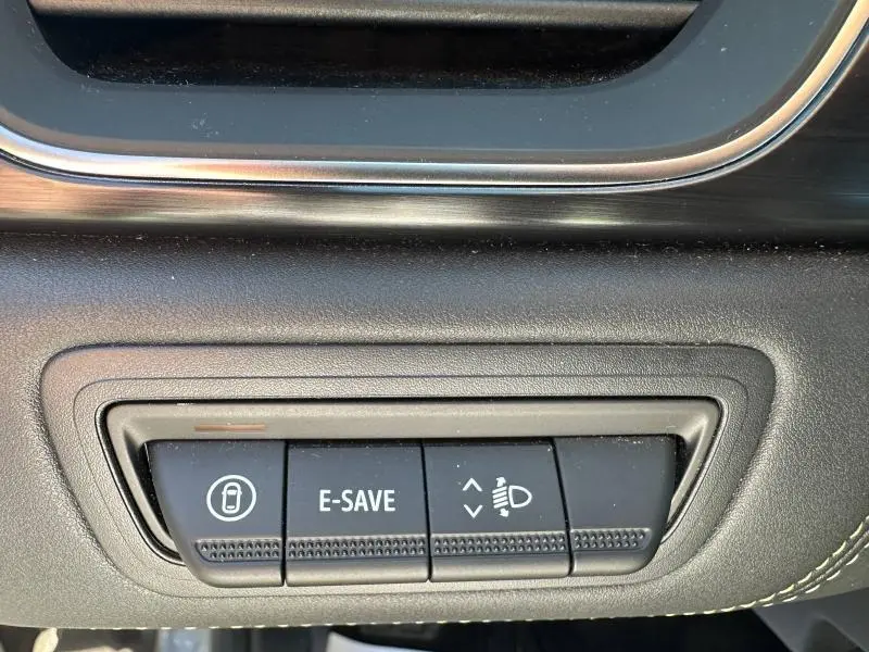 Gros plan sur les boutons de commande noirs du tableau de bord du Renault Symbioz rouge, avec fonction E-SAVE visible.