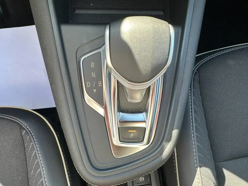 Vue rapprochée du levier de vitesses automatique noir et chrome de la Renault SYMBIOZ 2025, entouré de sièges noirs.