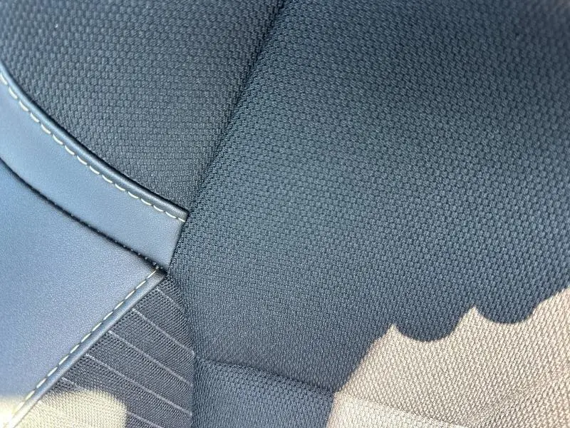 Détail en gros plan du tissu et surpiqûres du siège avant côté conducteur du Renault Symbioz rouge 2025.