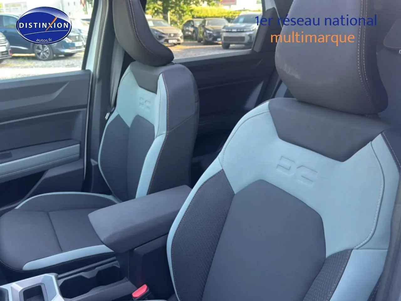 Gros plan sur les sièges avant bleu clair et noir avec accoudoir central du Dacia Bigster 2026 intérieur.
