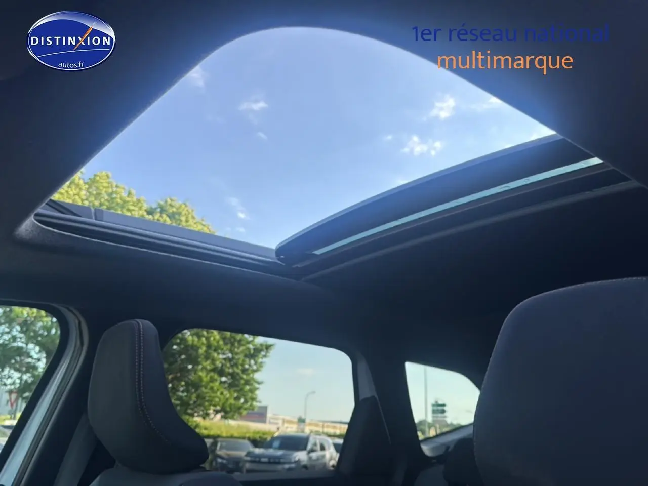 Vue intérieure du toit ouvrant panoramique en verre du Dacia Bigster blanc, avec ciel bleu visible à travers l'ouverture.