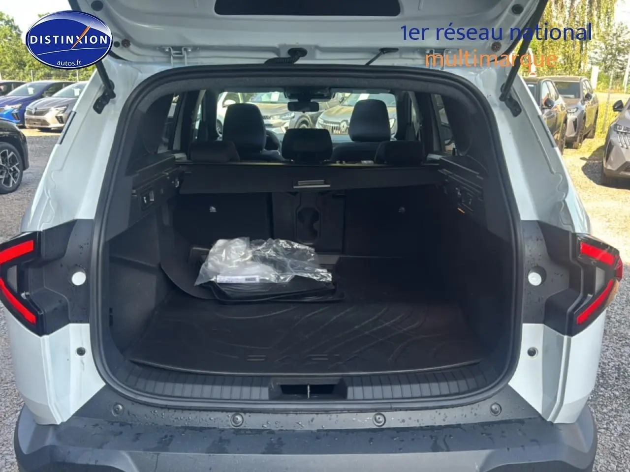 Vue arrière ouverte du coffre blanc du Dacia Bigster 2026 avec tapis de coffre et banquette arrière visible.