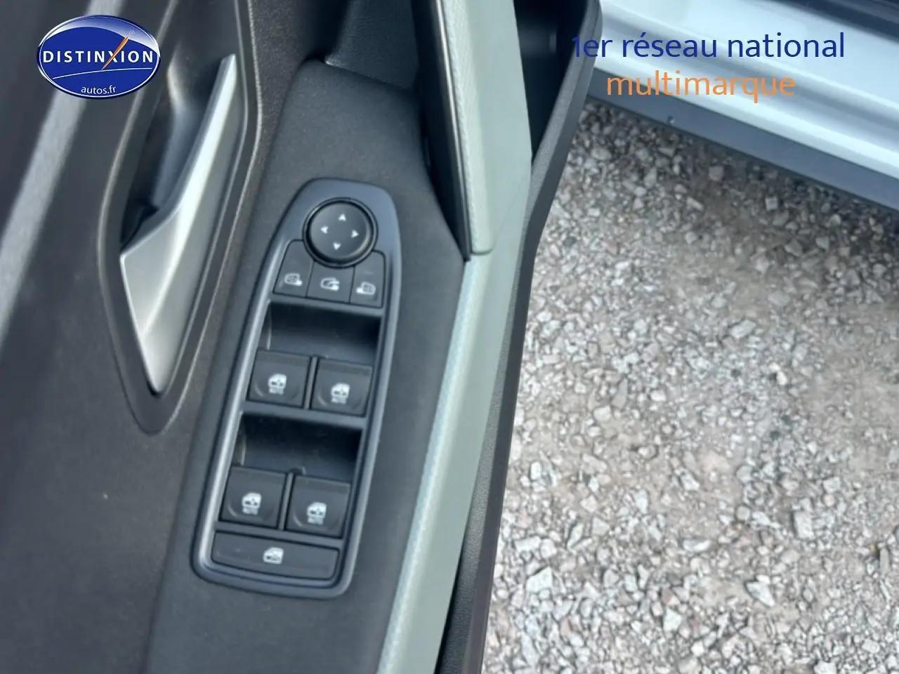 Gros plan sur la commande des vitres électriques côté conducteur d'une Dacia Bigster blanche, porte ouverte.