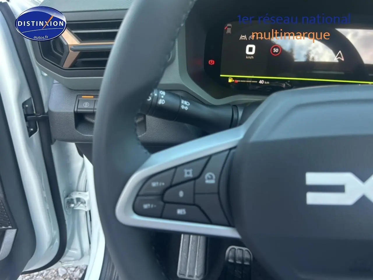 Gros plan sur le volant multifonction et le tableau de bord numérique du Dacia Bigster blanc, côté conducteur ouvert.
