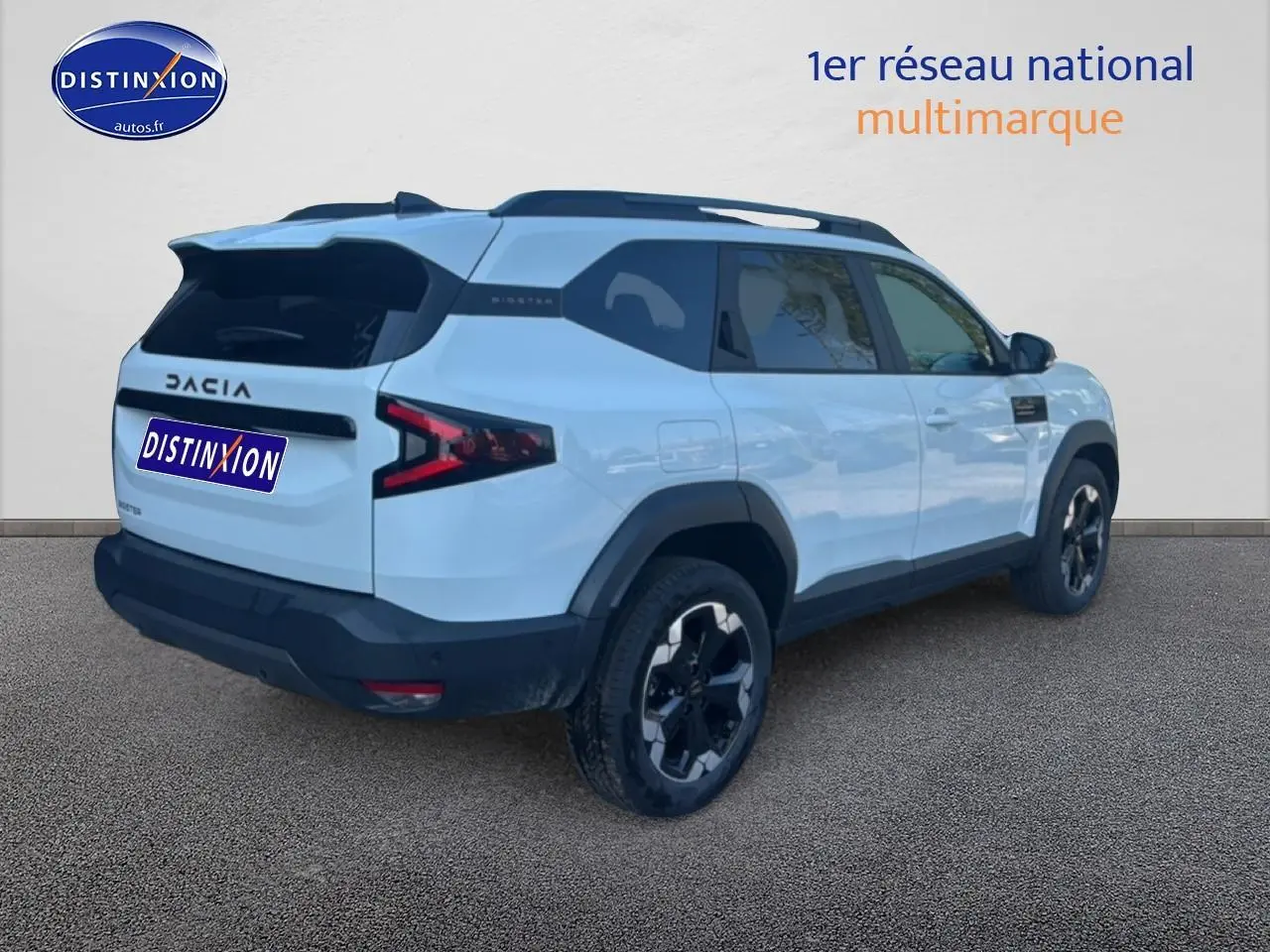 Vue 3/4 arrière droite d'un Dacia Bigster blanc 2026 avec barres de toit et jantes alu noires.