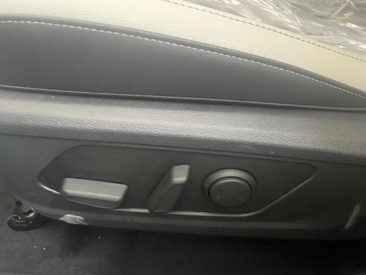 Détail des commandes de réglage électrique du siège avant en cuir noir du Kia Sportage Hybride blanc 2026.