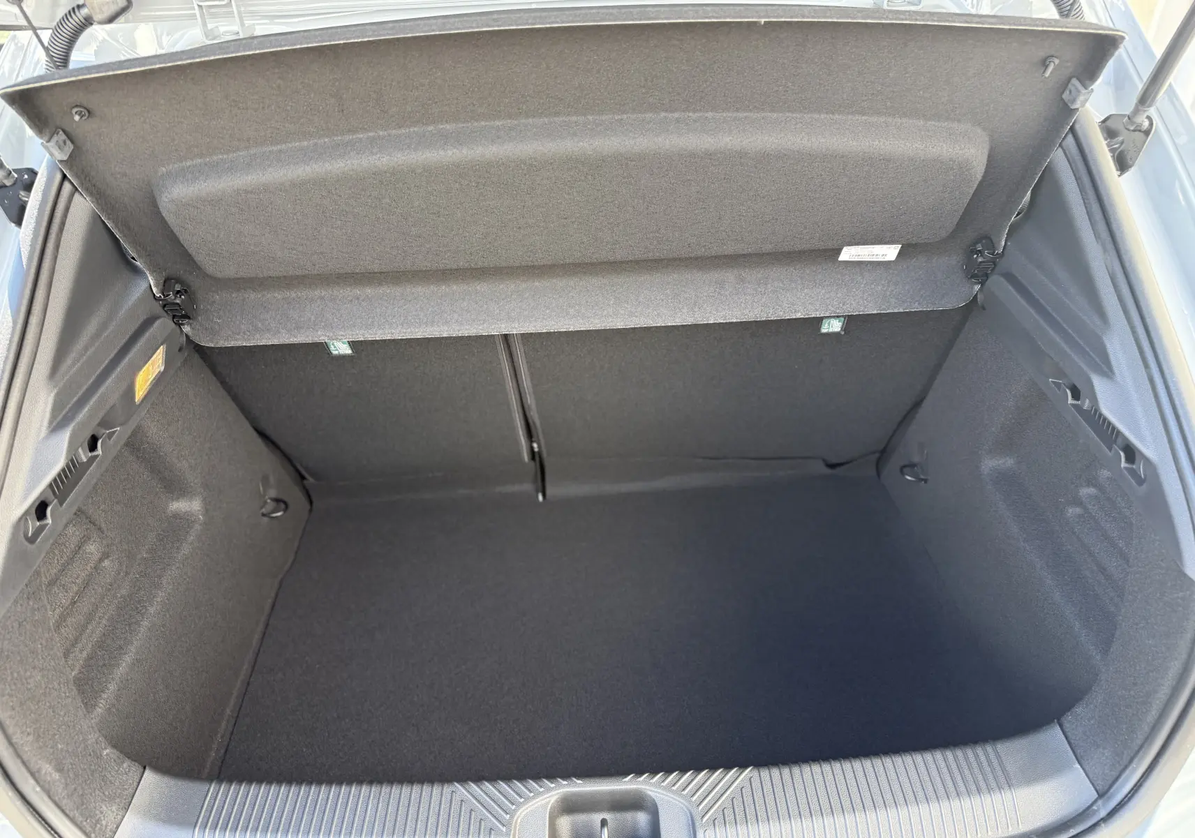 Coffre ouvert vu de dessus de la Renault Clio VI TCe 115 Techno gris Rafale, montrant un espace de rangement propre et vide.