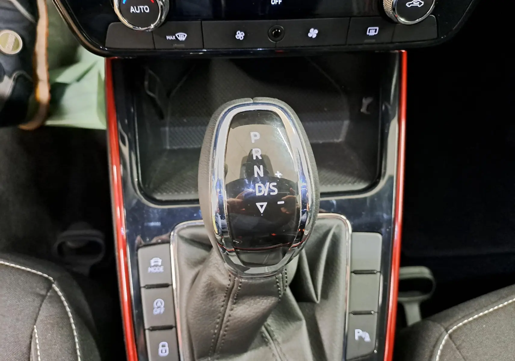 Le levier de vitesses automatique DSG7 de la Skoda Fabia 2024, entouré d'inserts rouges et boutons de contrôle.