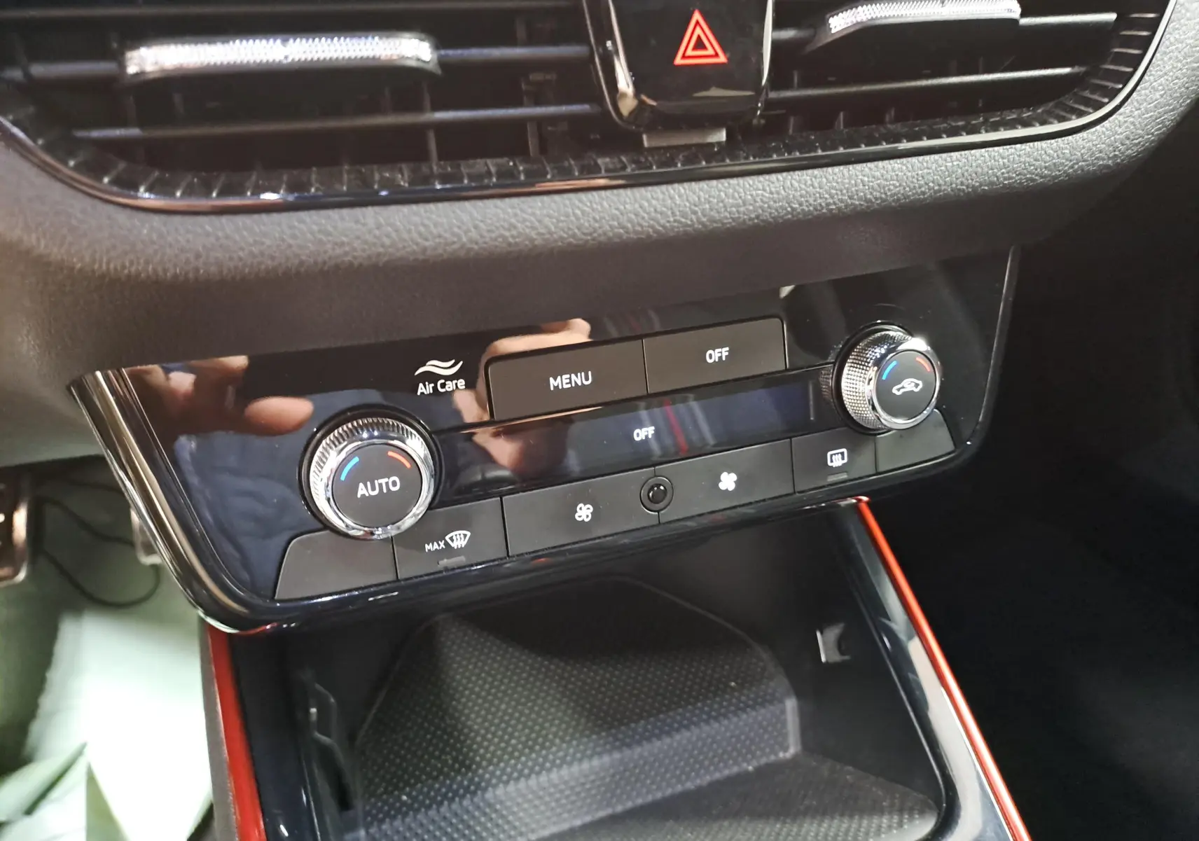 Gros plan sur la console centrale noire brillante de la Skoda Fabia 2024 avec commandes climatisation et bouton hazard rouge.