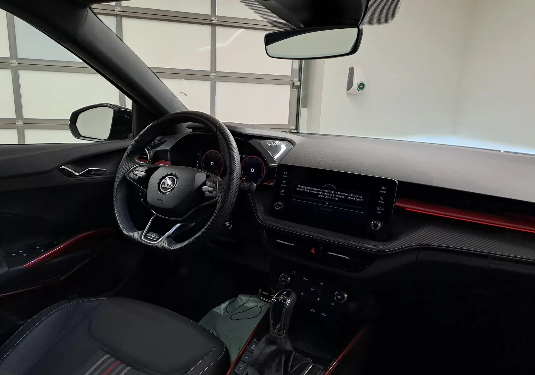 Intérieur avant droit de la Skoda Fabia 2024 noir Magic Nacré avec tableau de bord numérique et éclairage d'ambiance rouge.