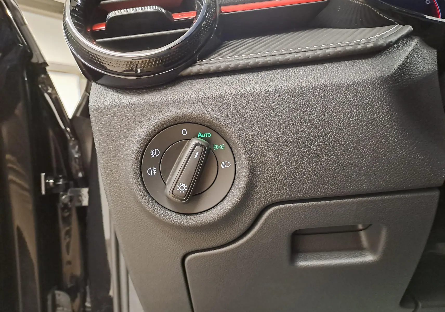 Gros plan sur le bouton de commande des phares à gauche du tableau de bord d'une Skoda Fabia 2024 noir Magic Nacré.