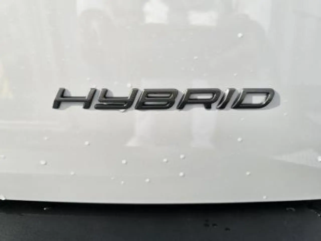 Gros plan sur l’inscription HYBRID noire sur la carrosserie blanche d’un Peugeot 2008 2025.