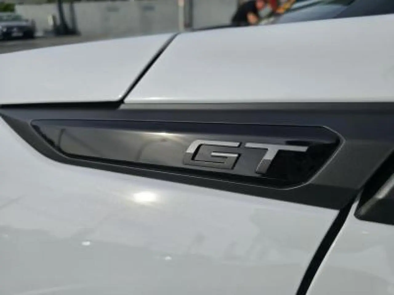 Gros plan sur l'emblème GT noir brillant sur la portière blanche du Peugeot 2008 II hybride 2025.