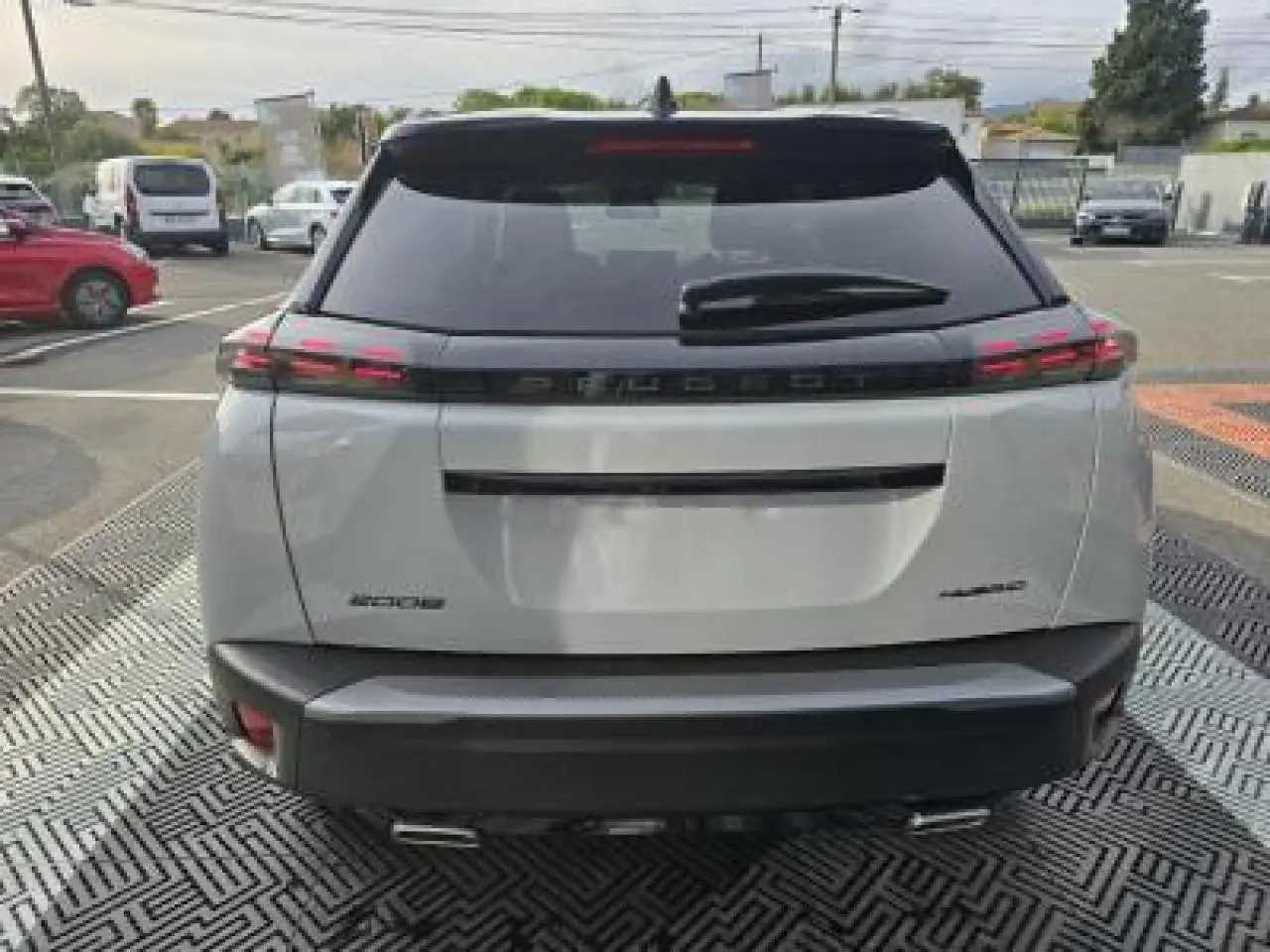 Vue arrière d'un Peugeot 2008 blanc Okenite avec toit noir, feux LED 3 griffes et double sortie d'échappement chromée.