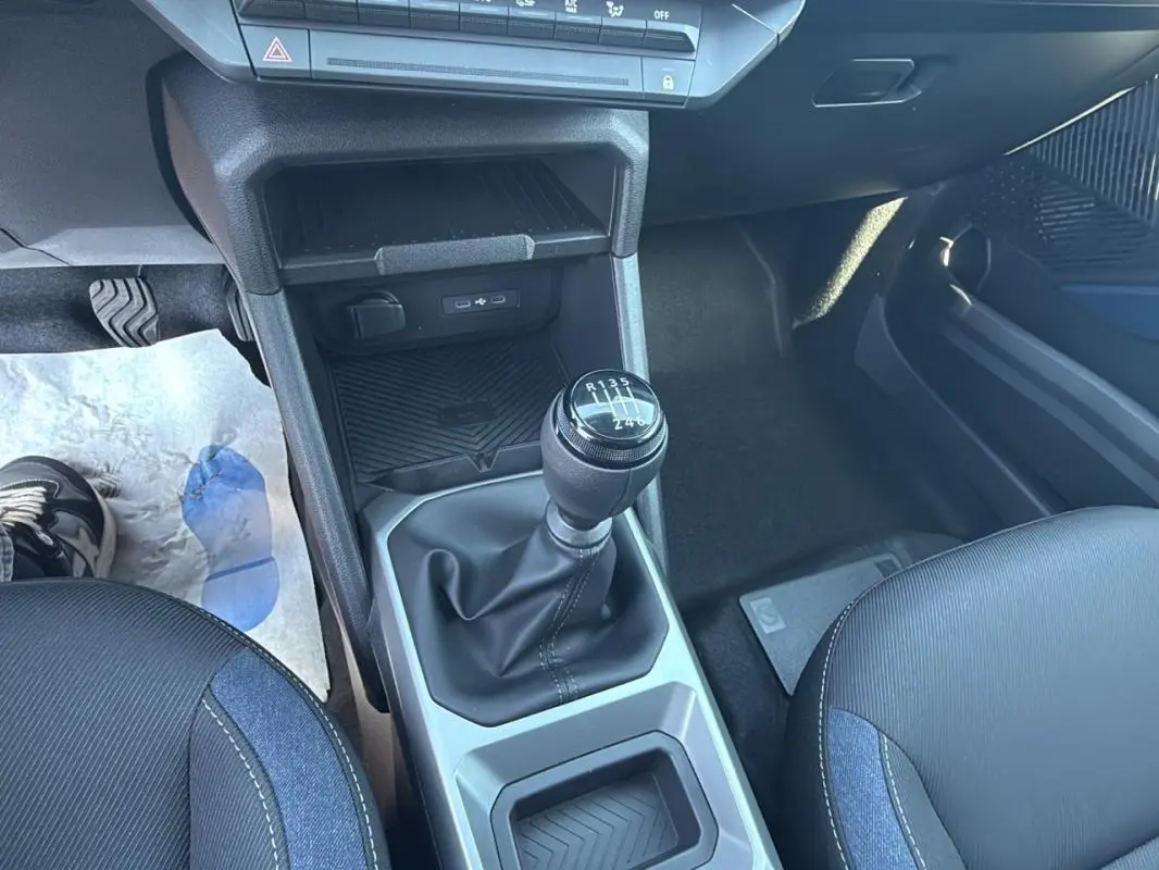 Gros plan sur la console centrale du Dacia Duster 2025, montrant le levier de vitesse manuel et les sièges noirs.