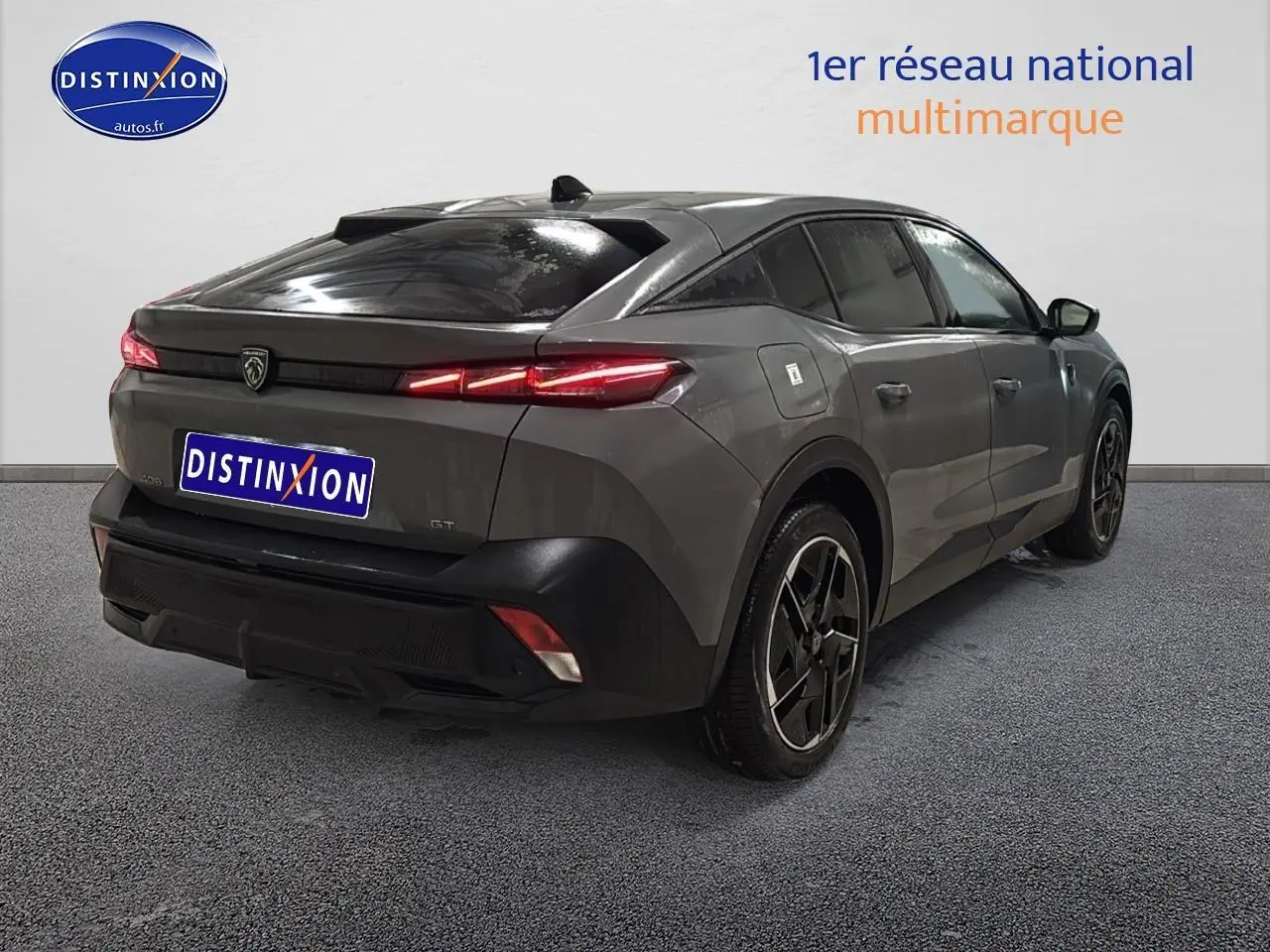 Vue 3/4 arrière droite d'une Peugeot 408 Hybrid 145 GT gris sélénite avec feux arrière LED allumés et jantes alu noires.