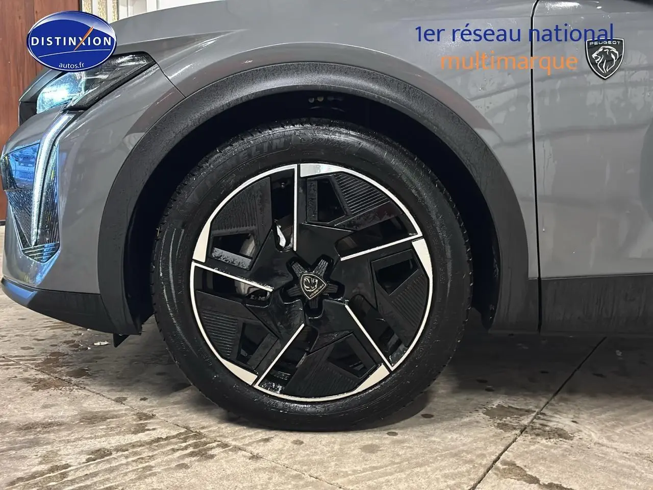 Gros plan sur la roue avant gauche et partie avant gris sélénite d’une Peugeot 408 Hybrid 145 GT e-DCS6 2025.