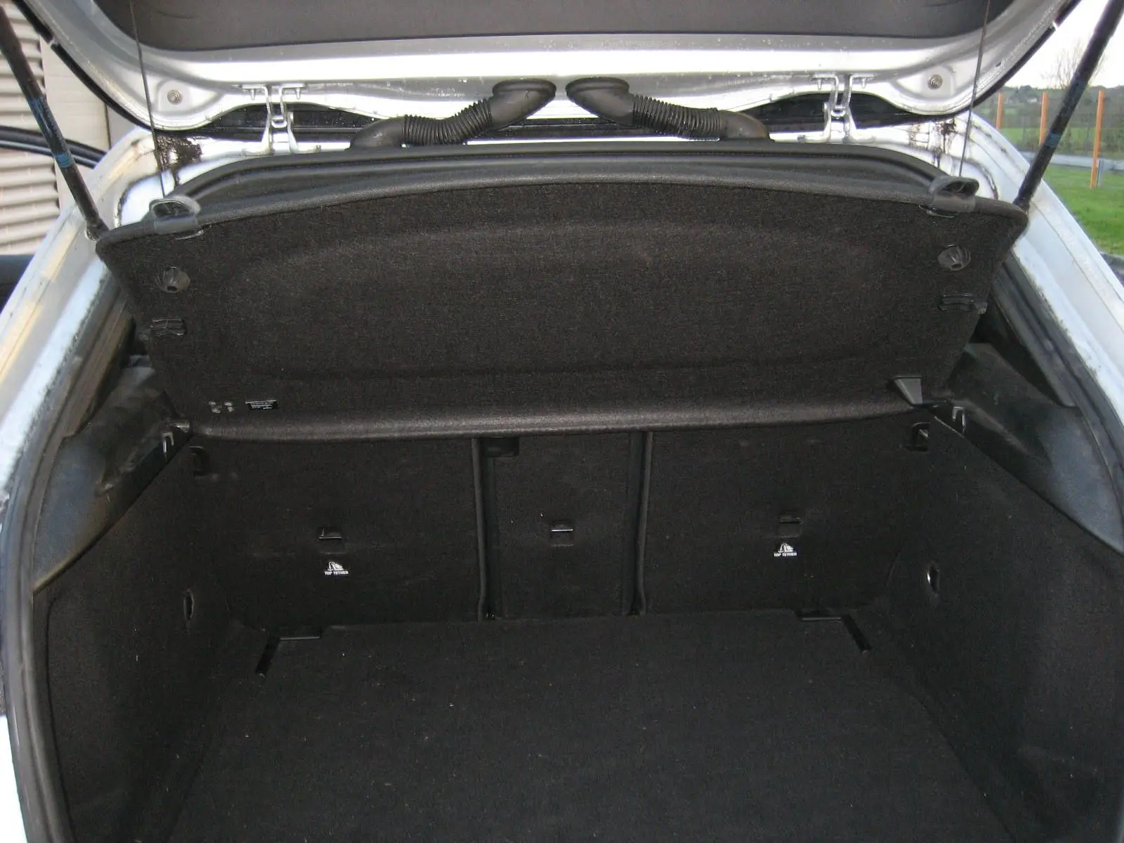 Coffre ouvert vu de l'arrière d'une Mercedes Classe A180D gris, montrant l'espace de chargement et la trappe de coffre.