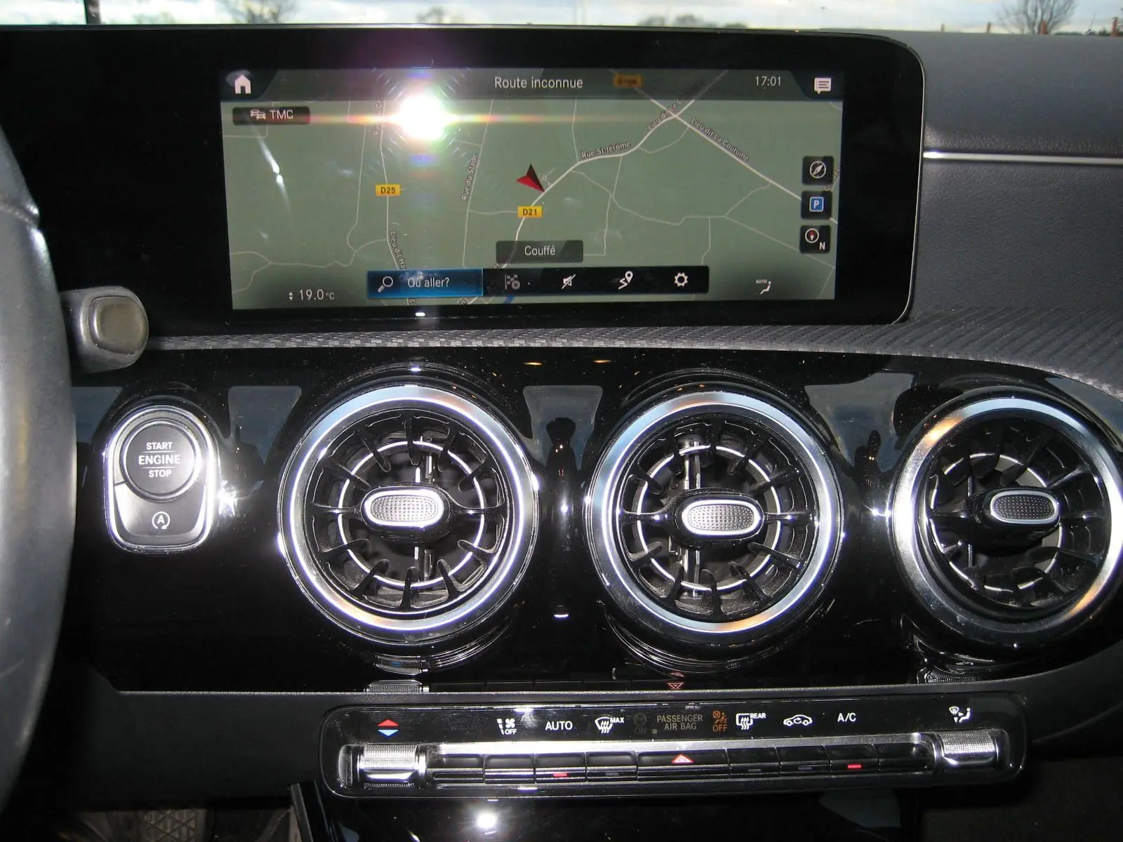 Vue rapprochée de la planche de bord noire d’une Mercedes Classe A 180d 2021 avec écran GPS et aérateurs ronds chromés.