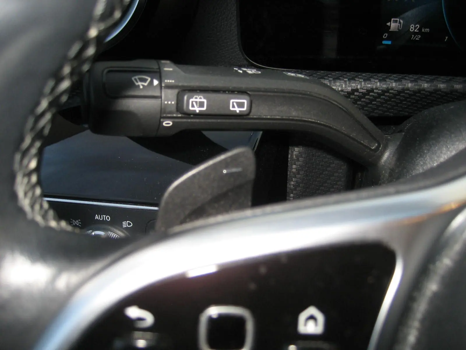 Gros plan sur la commande d’essuie-glace et palette de changement de vitesse du volant noir d’une Mercedes Classe A gris 2021.