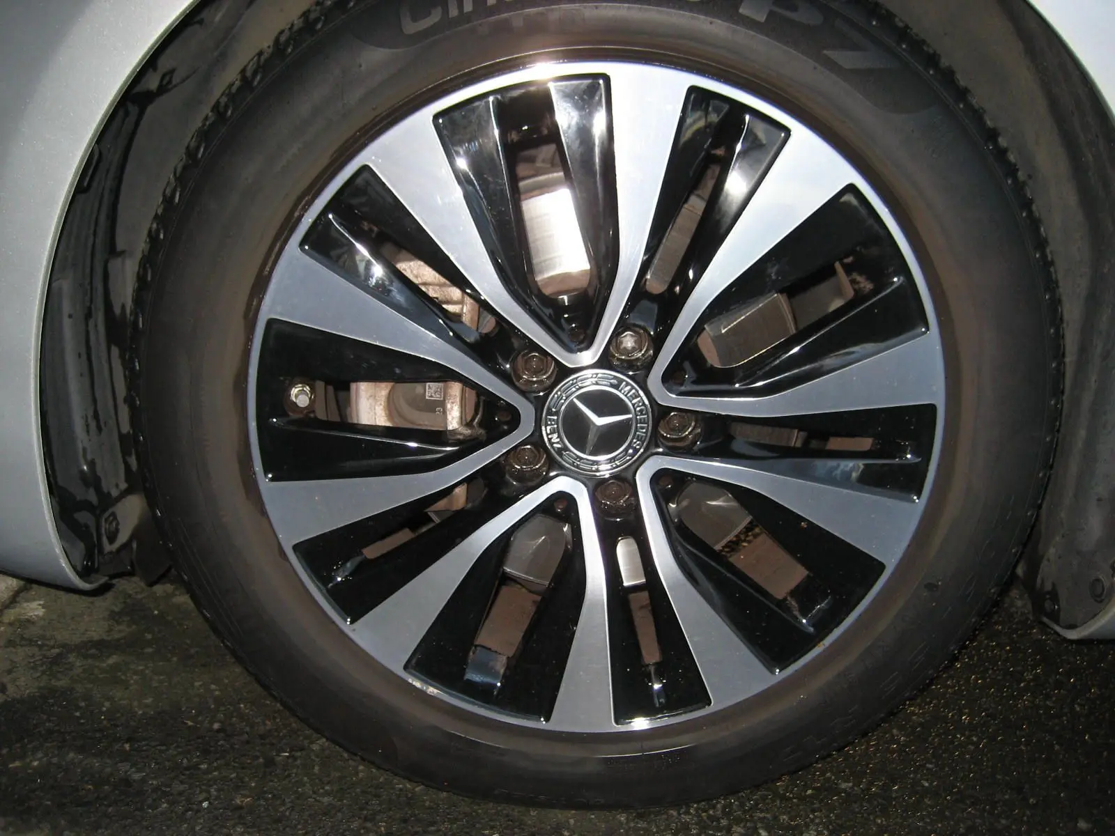 Gros plan sur la jante bi-ton noire et argent d'une Mercedes Classe A180D gris 2021, avec logo étoile central.