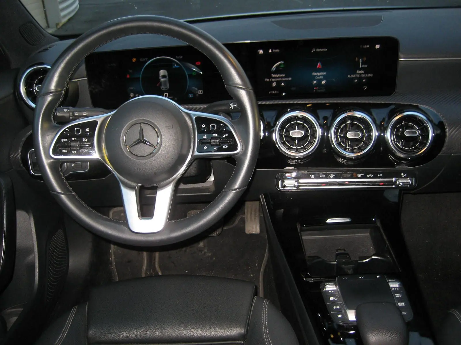 Vue intérieure centrée sur le volant cuir noir et le tableau de bord numérique de la Mercedes Classe A 180d Business Line.