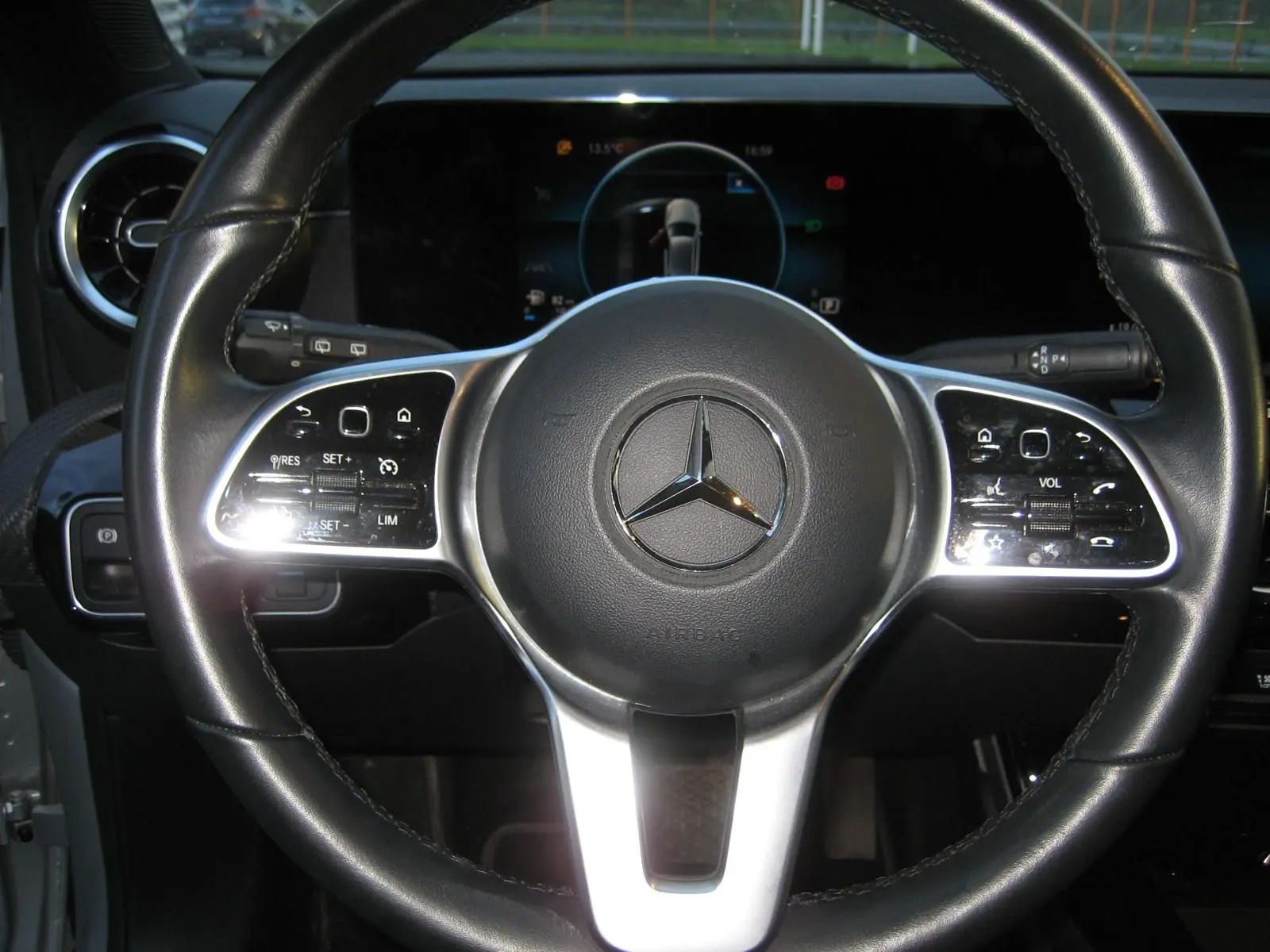 Vue rapprochée du volant cuir noir d’une Mercedes Classe A gris 2021 avec commandes intégrées et écran digital en arrière-plan.