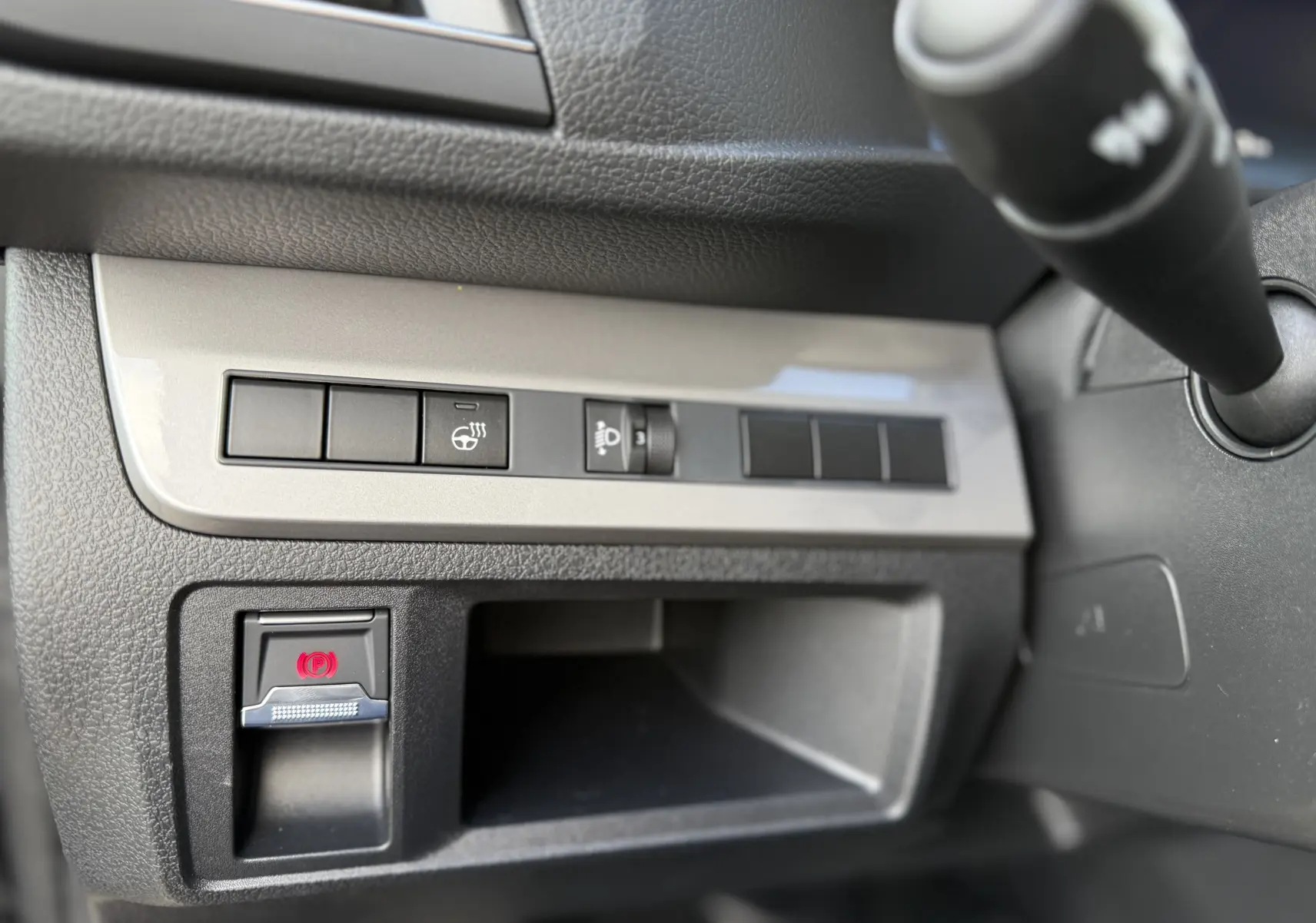 Vue rapprochée du tableau de bord côté gauche d’un Citroën Jumpy Cabine Approfondie noir Perla, avec commandes et frein à main électrique.