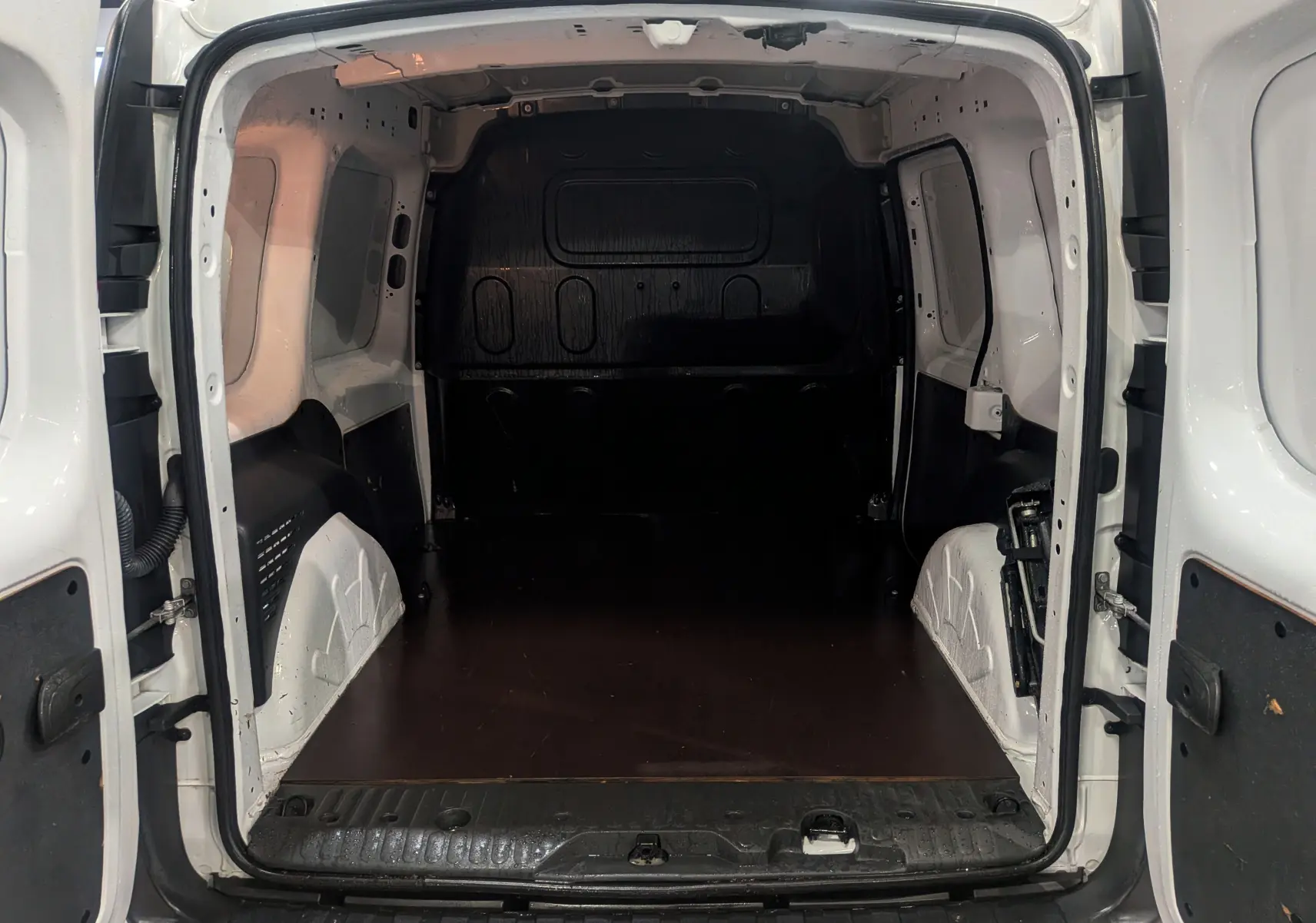 Vue arrière intérieure du Renault Kangoo Express blanc minéral 2020, montrant l’espace de chargement vide et les portes ouvertes.