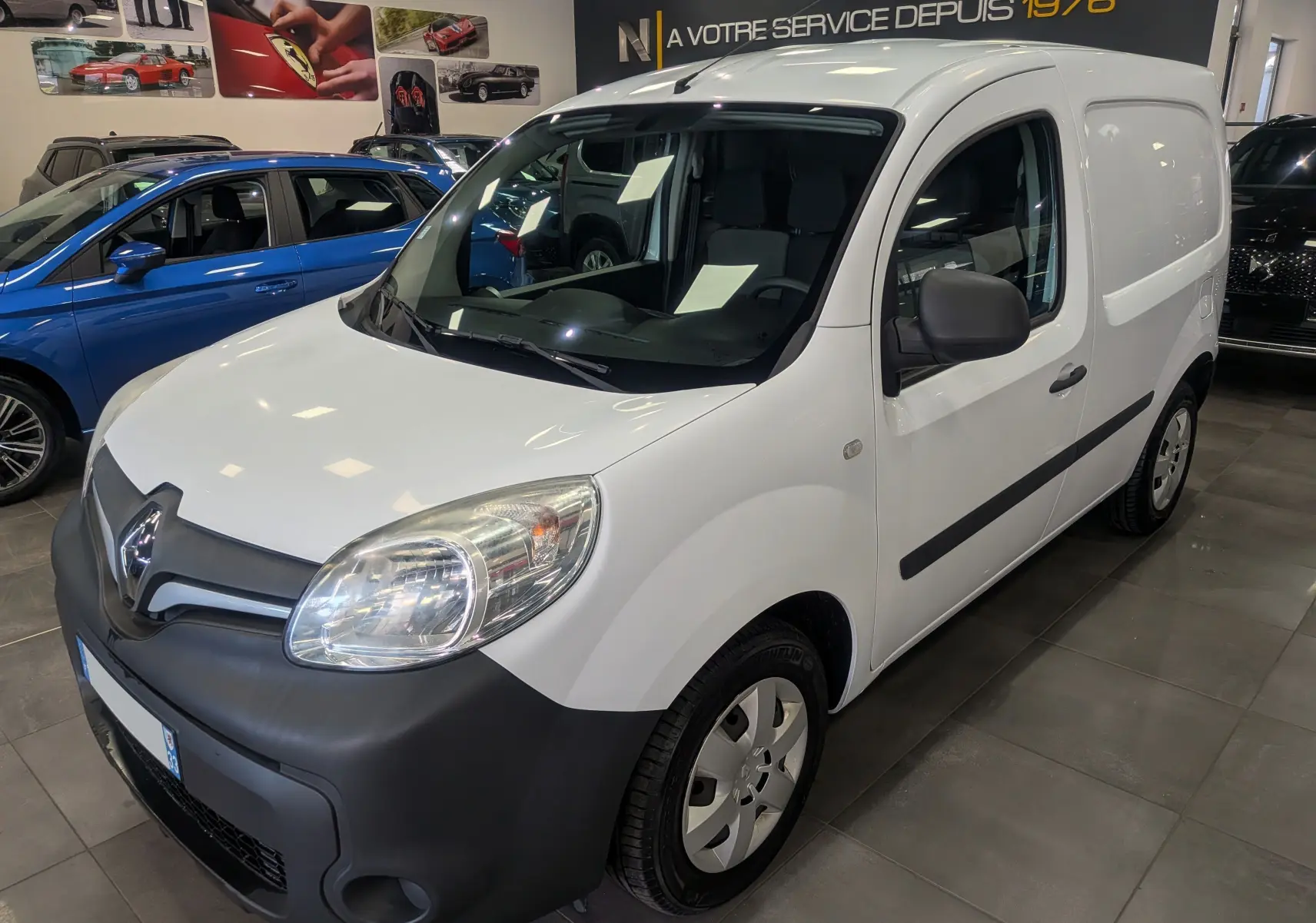 Renault Kangoo Express Blanc Minéral vu en 3/4 avant droit, utilitaire compact avec pare-chocs noirs mat et vitres teintées.